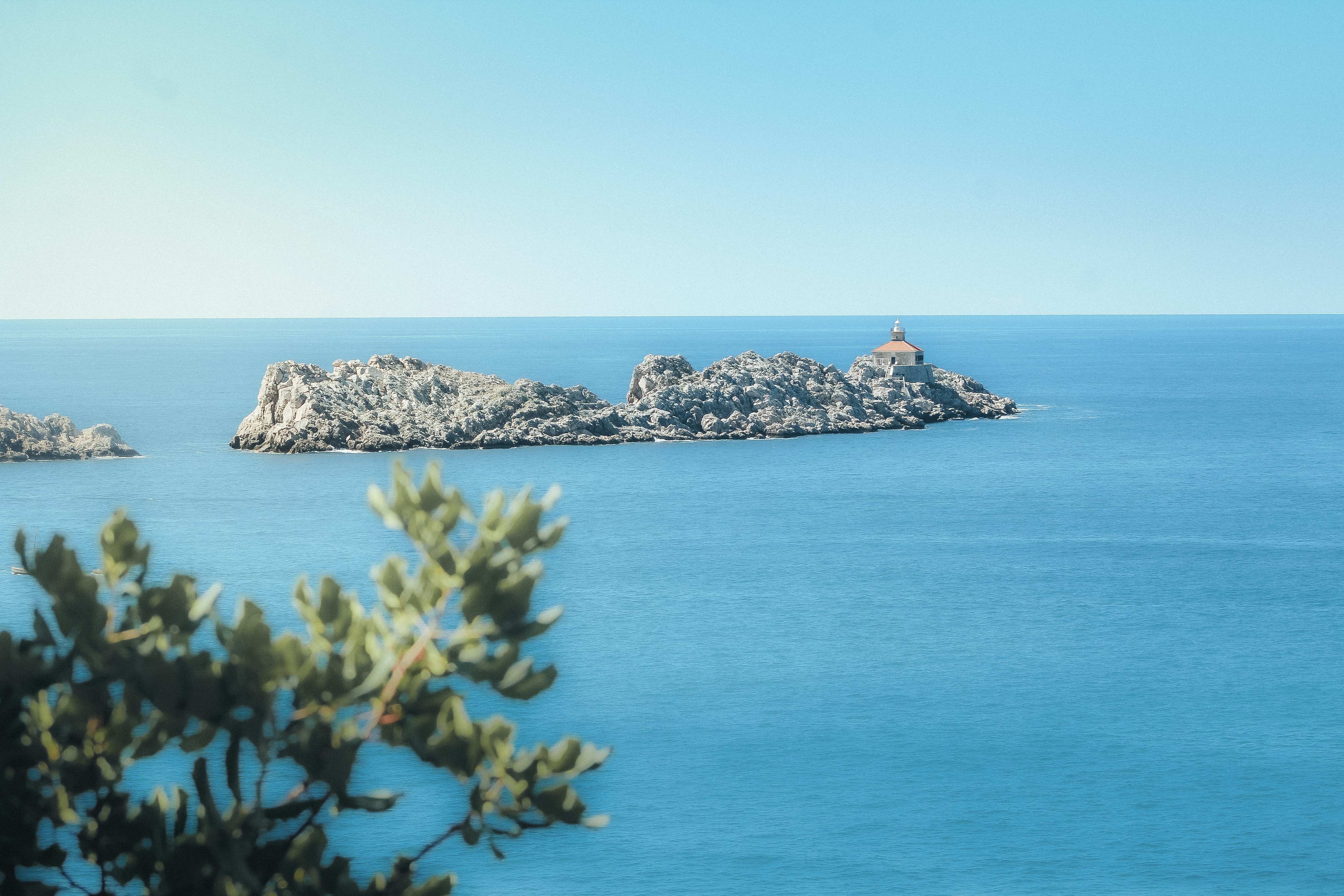 Rocky island with lighthouse in bright blue ocean