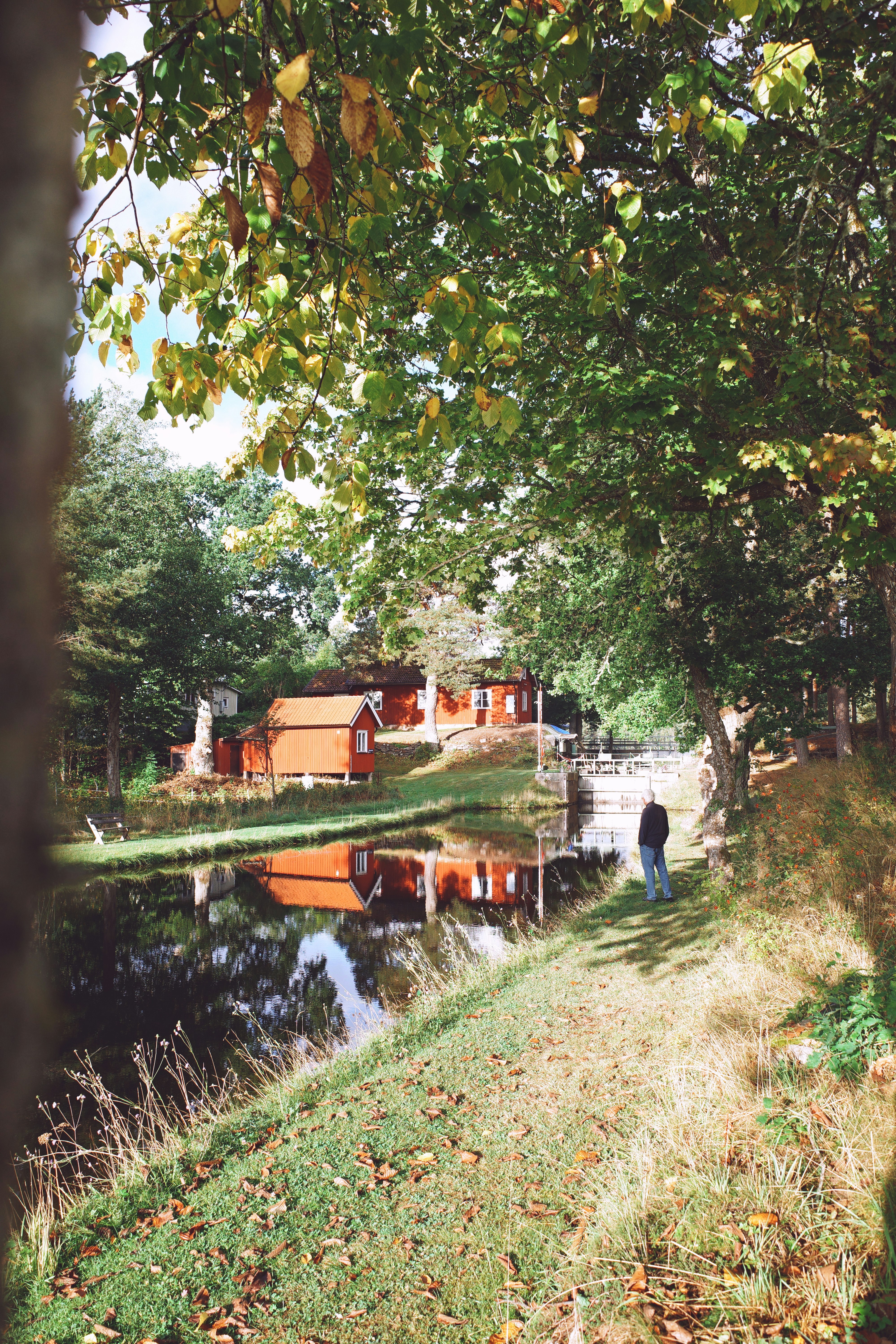 Red cabins by a canal with a person walking