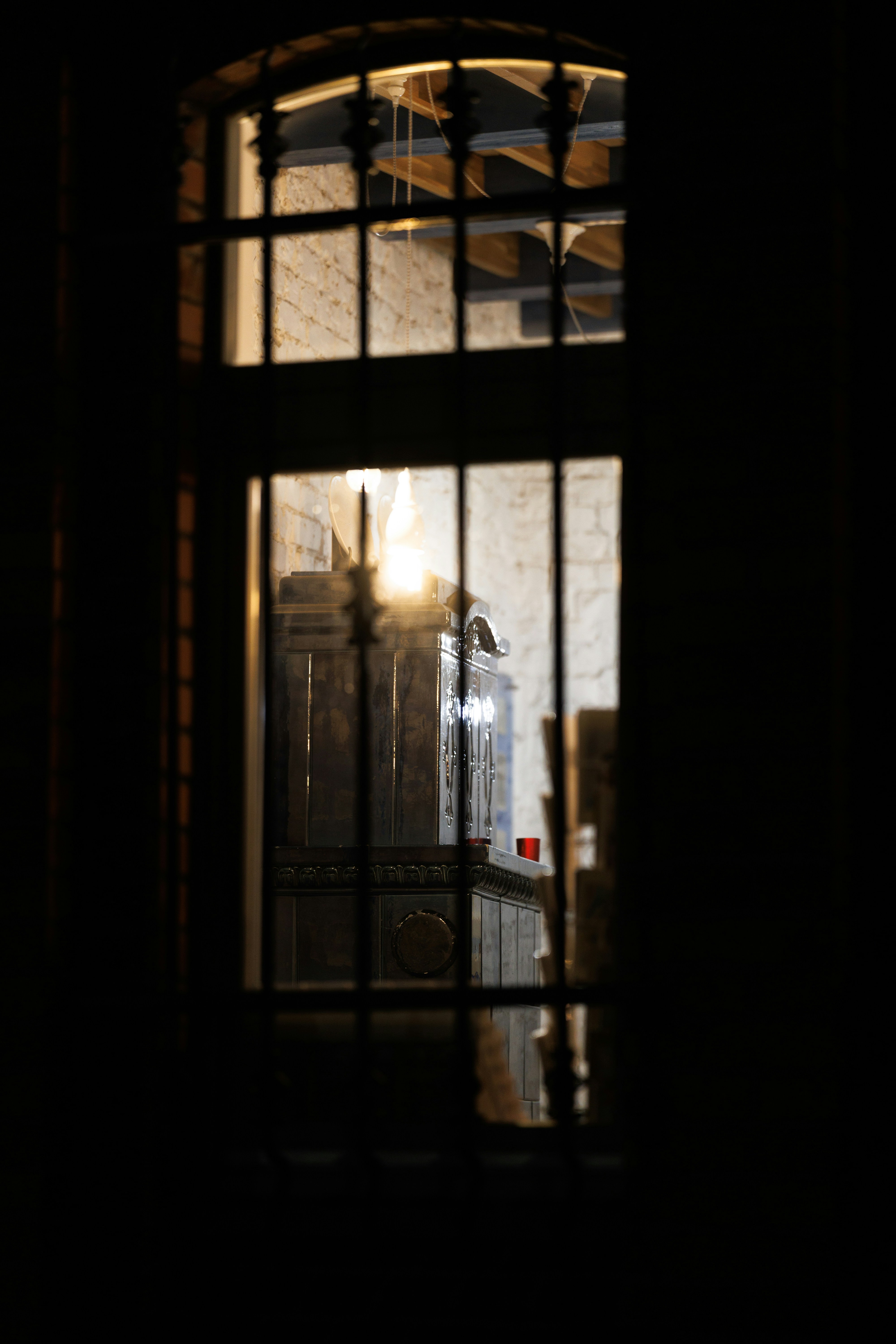 Ornate stove visible through a barred window at night.