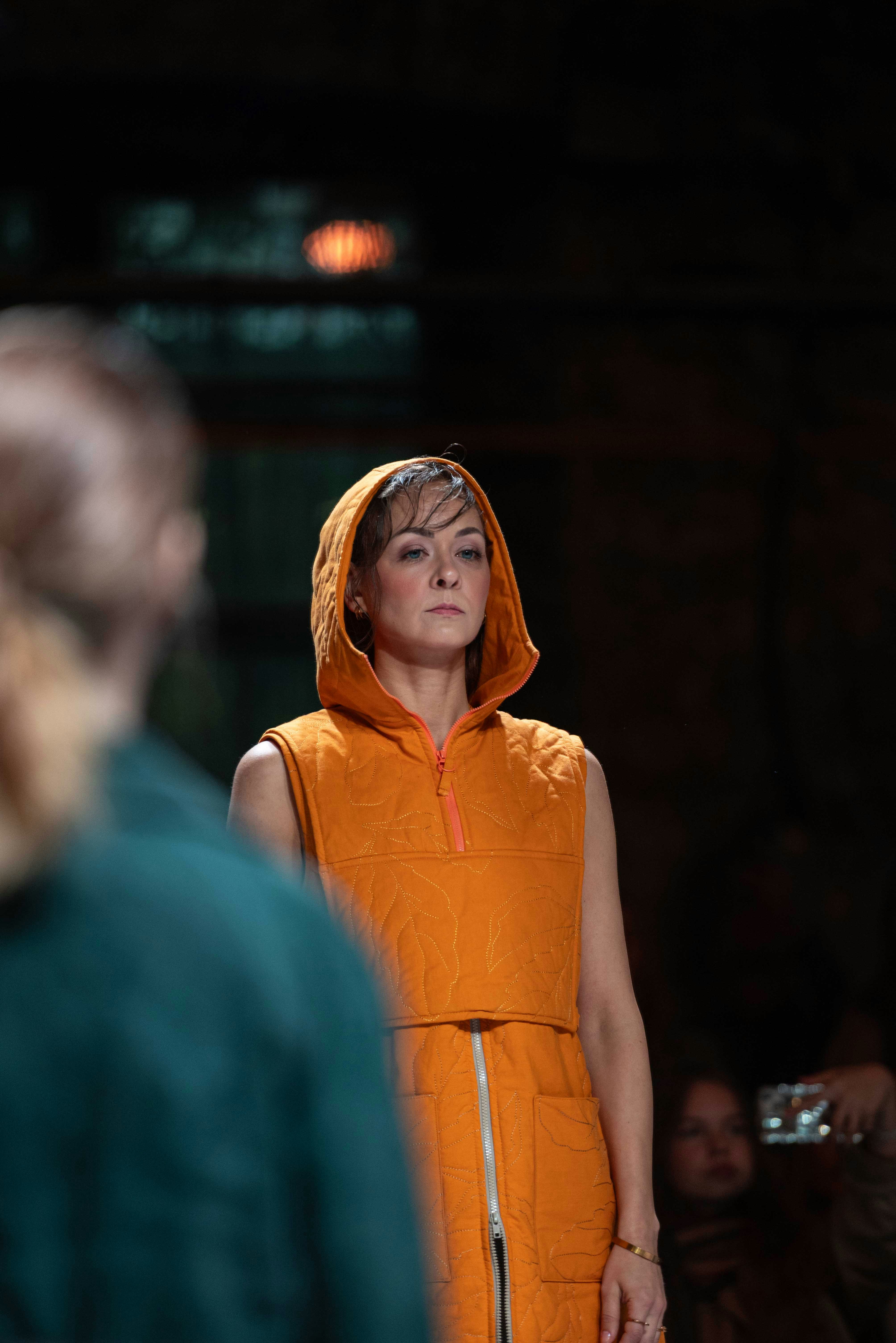 Woman in orange hooded vest on runway