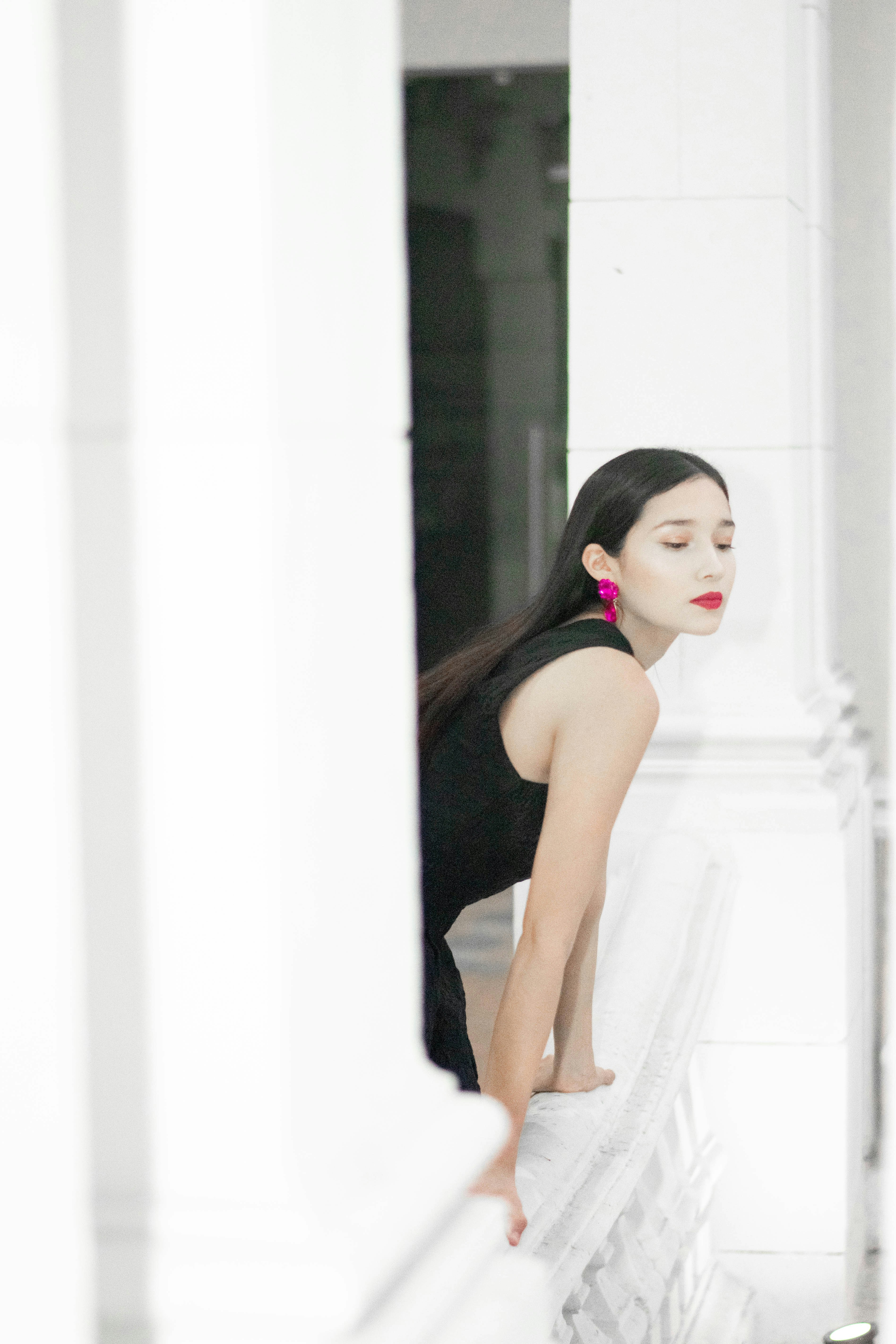 Wanita bergaun hitam dengan anting-anting merah muda