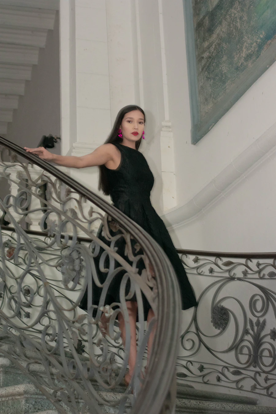 Model in a black dress on an ornate wrought-iron staircase