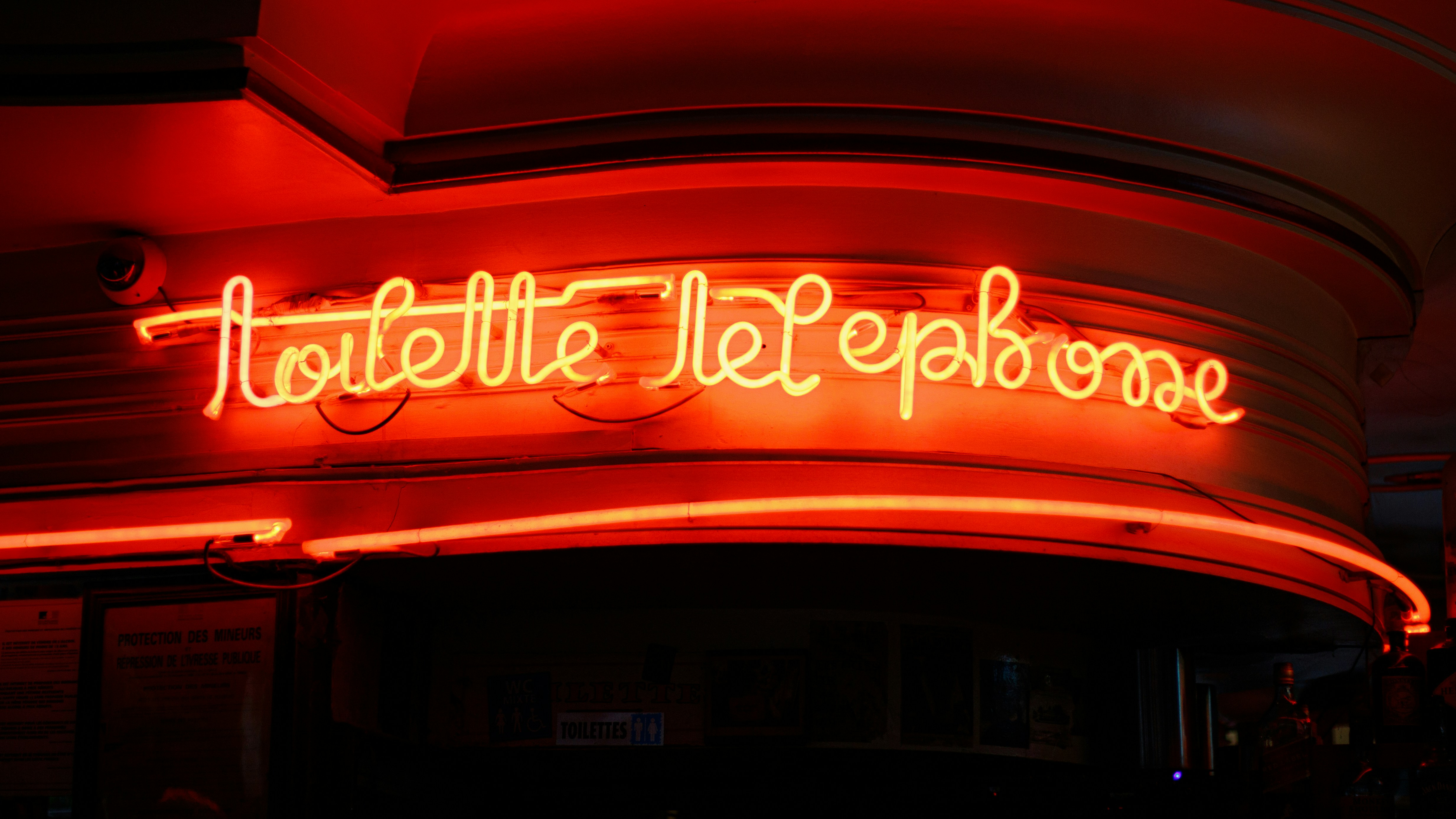Red neon sign spelling 'toilette telephone'