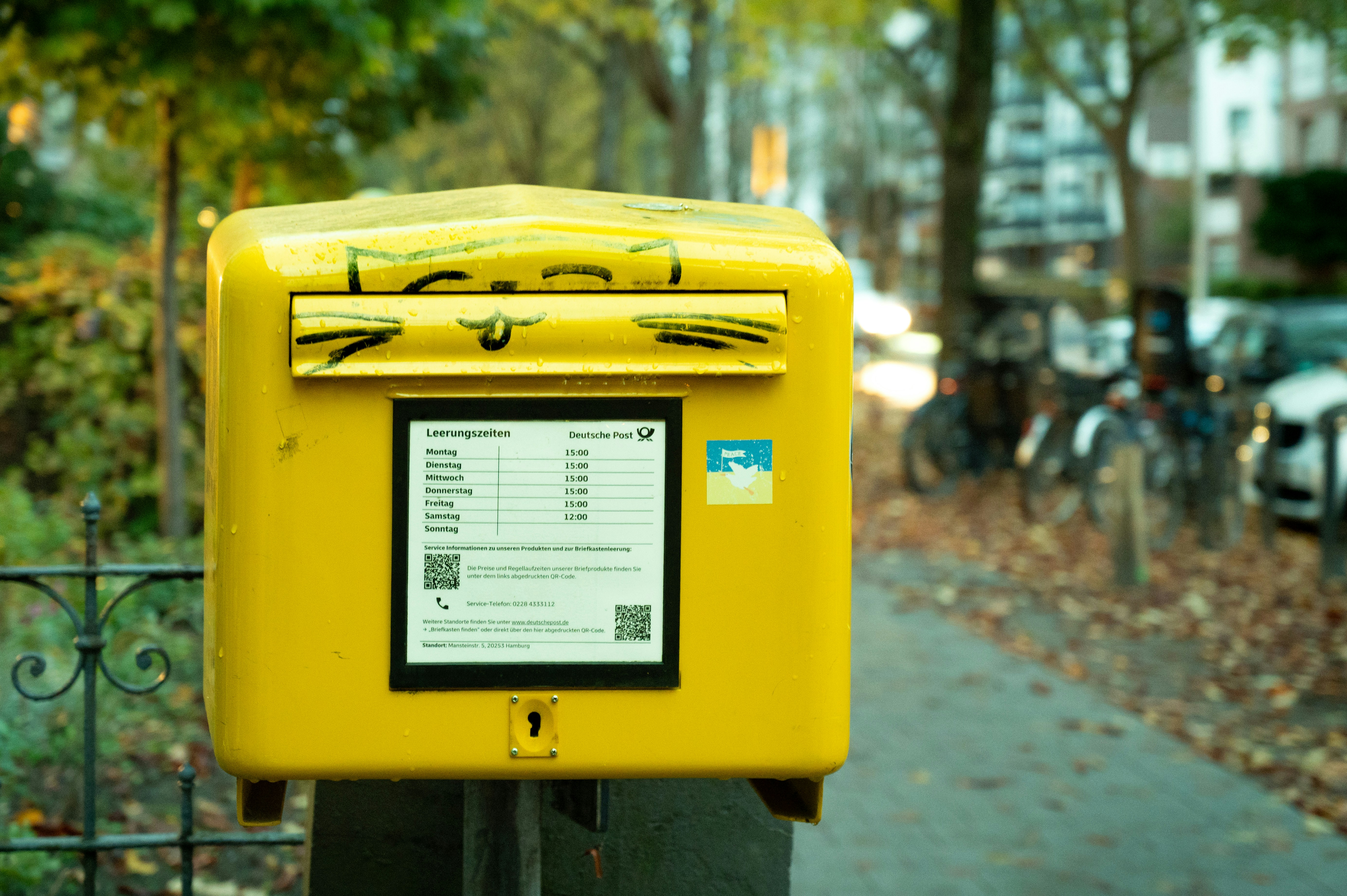 Yellow mailbox on a sidewalk with trees