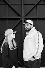 Two people wearing baseball caps and hoodies