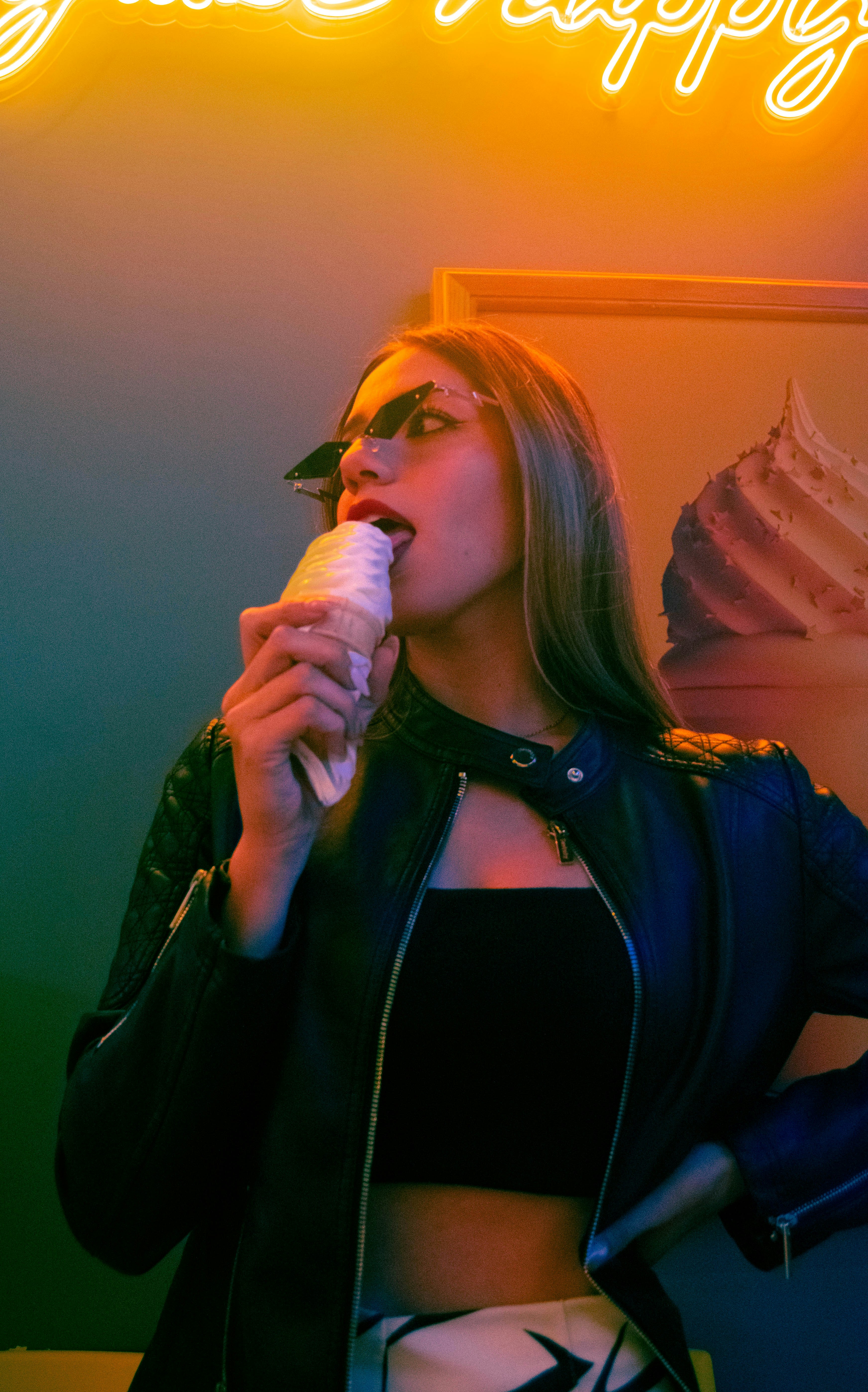 Woman eating ice cream cone under neon sign