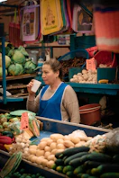 Woman drinking at a produce stall in a market.
