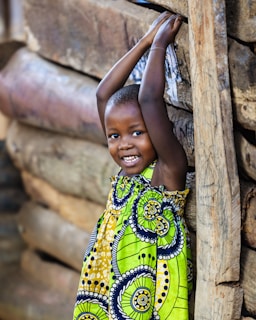 A young child in a colorful dress smiles broadly.
