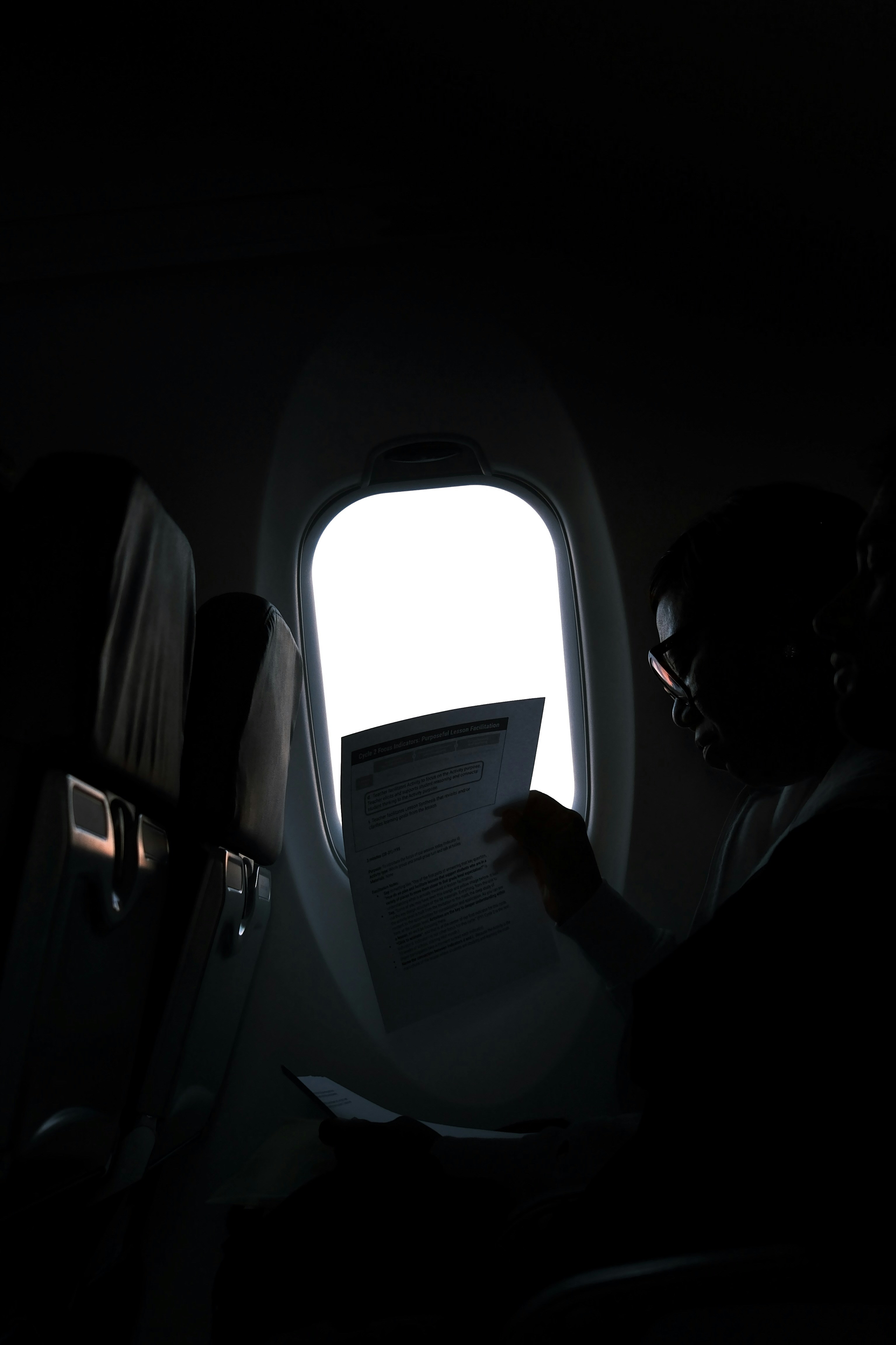 Person, die Dokumente am Flugzeugfenster liest