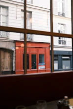 Red storefront seen through a window in paris
