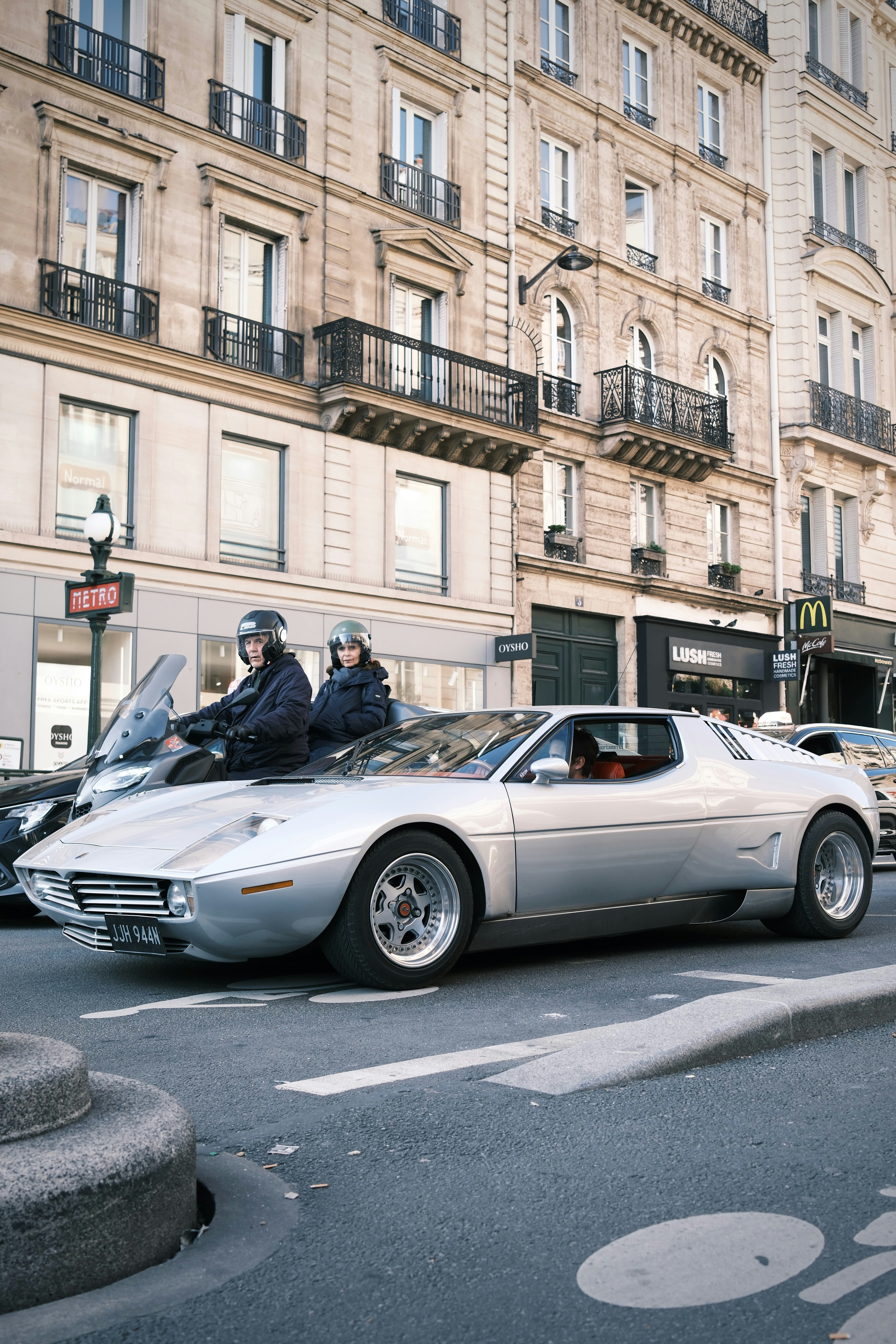 Silver vintage car with two people on motorcycle