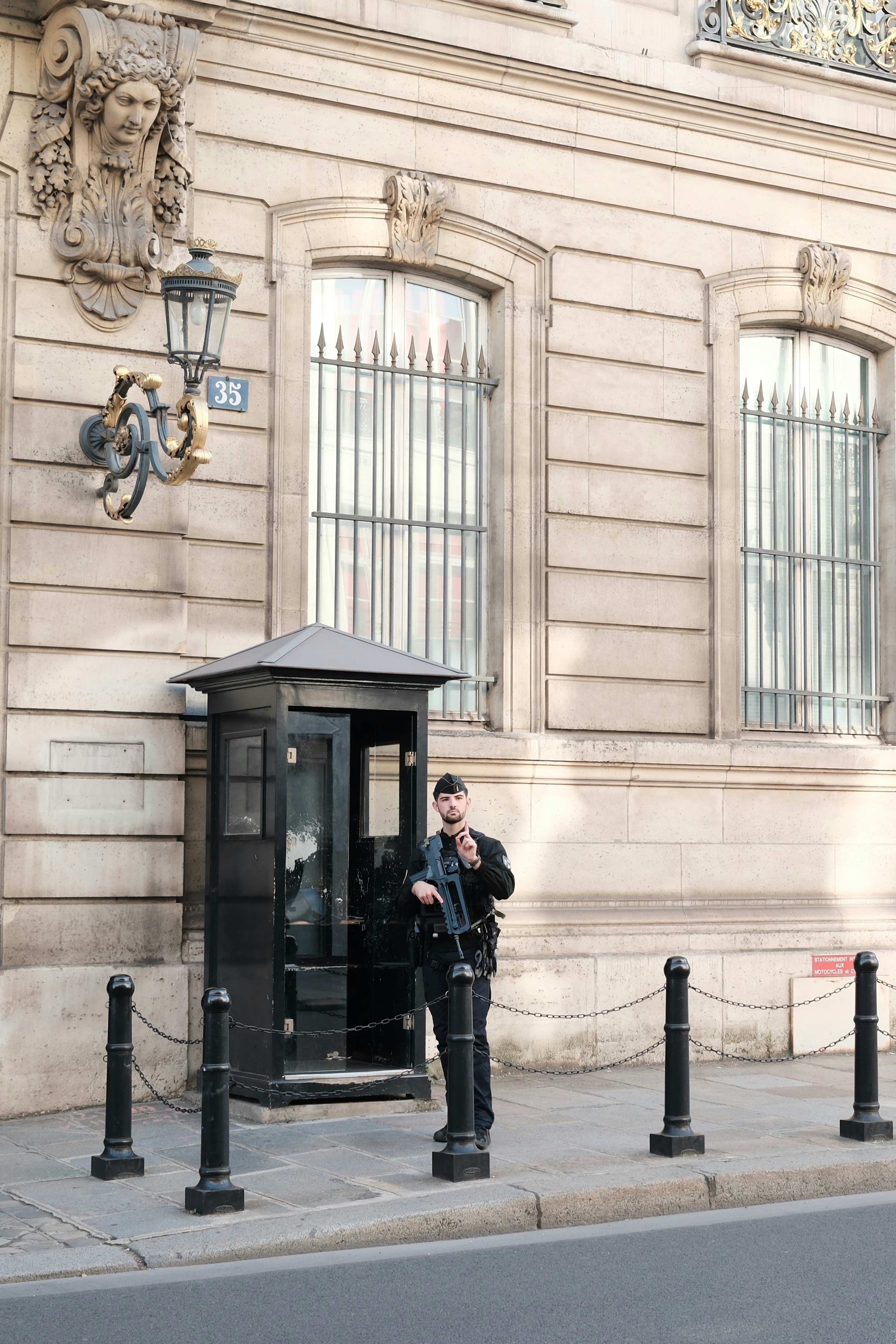 Guard standing outside a building with a rifle.
