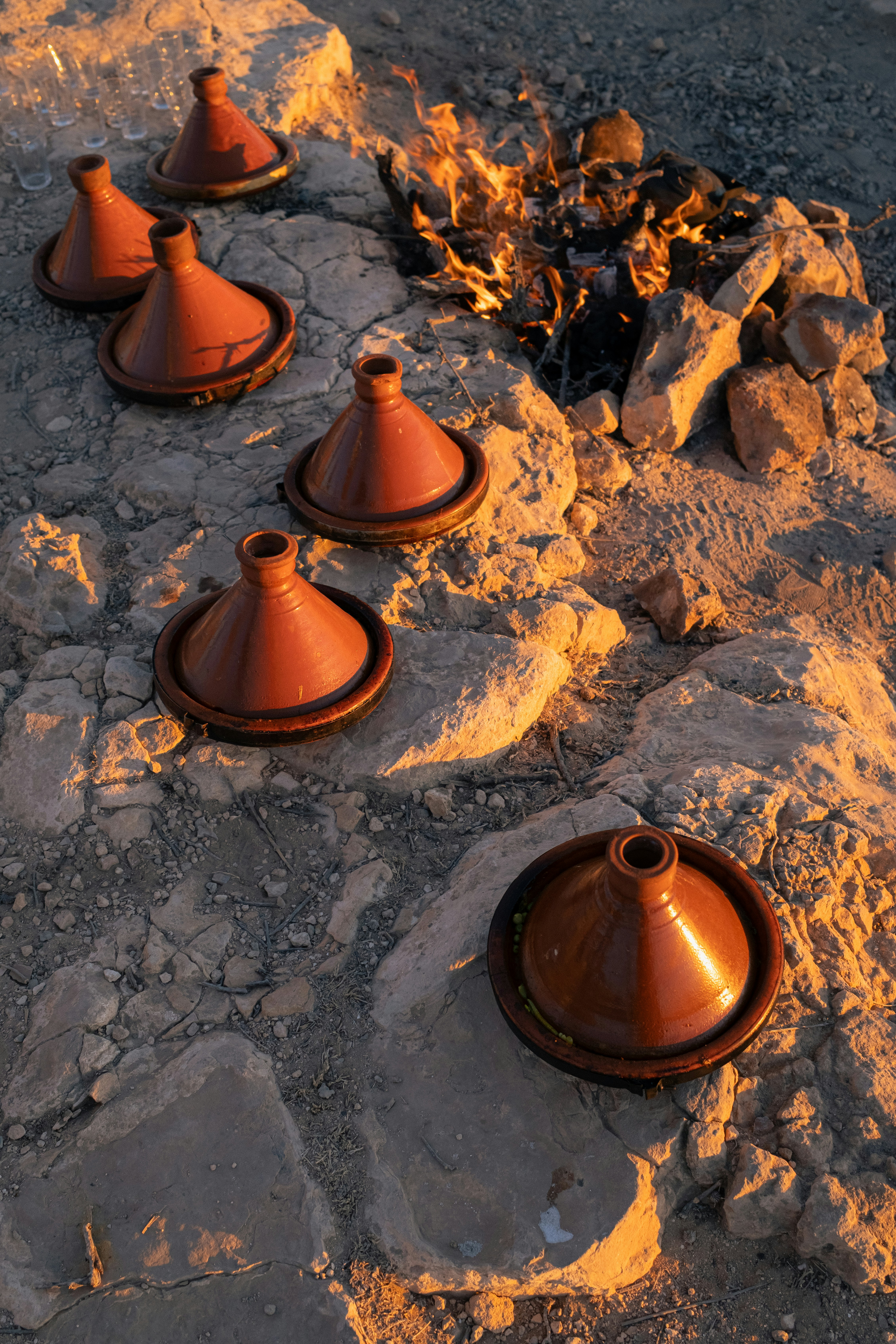 Several tagine pots arranged around a campfire