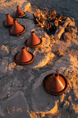 Several tagine pots arranged around a campfire