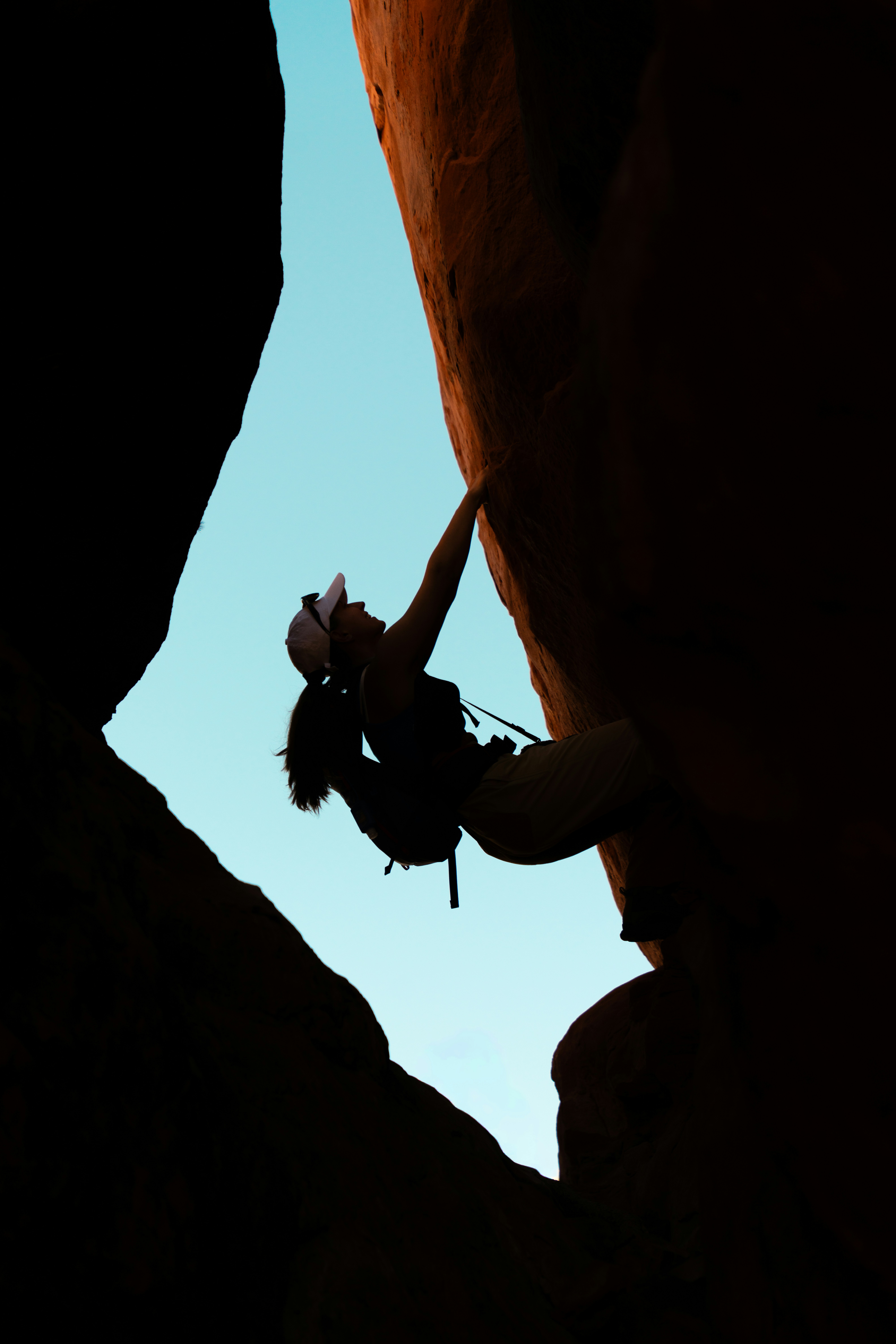 Silhouette of a woman rock climbing outdoors.
