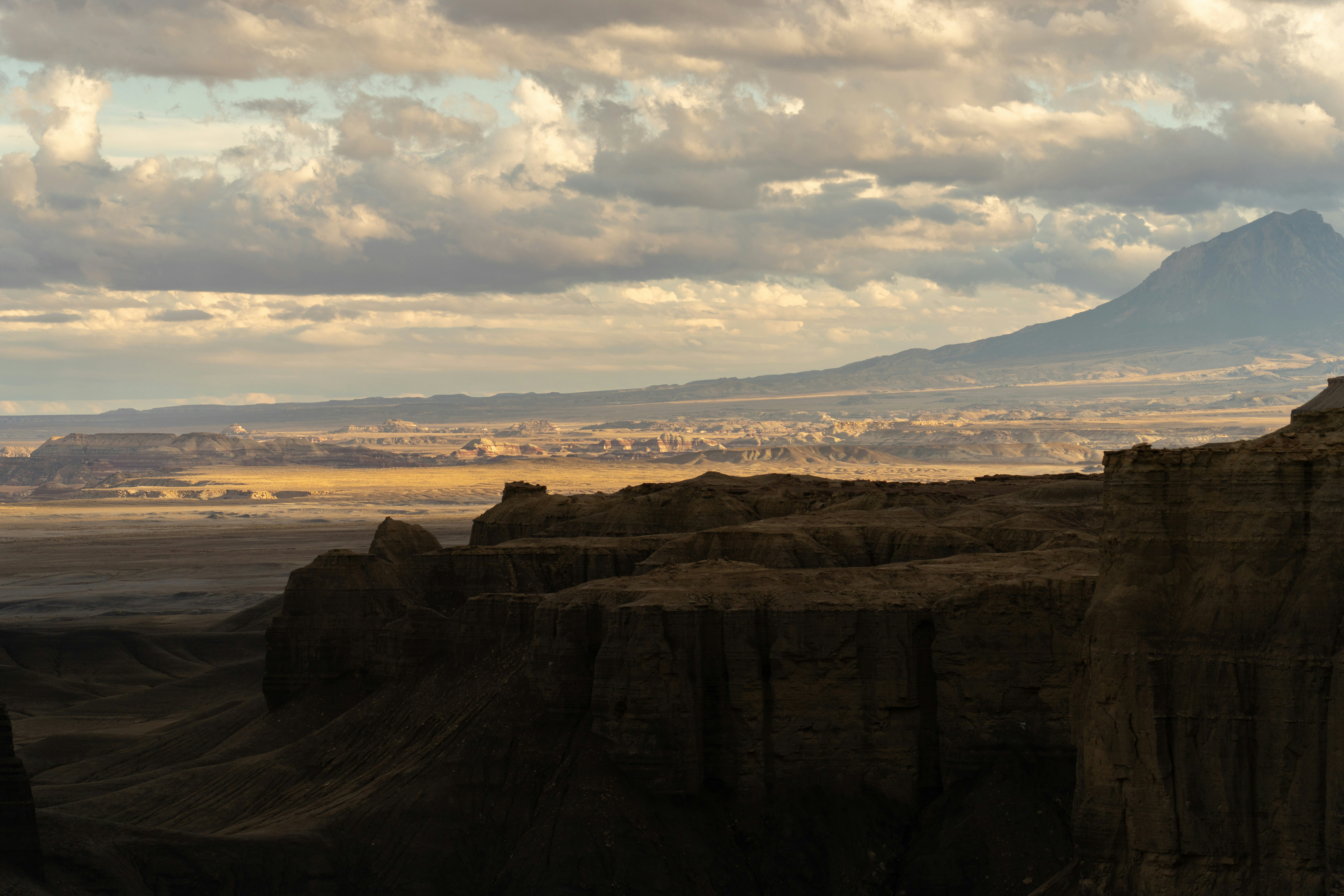 Dramatic desert landscape with rocky cliffs and distant mountains.