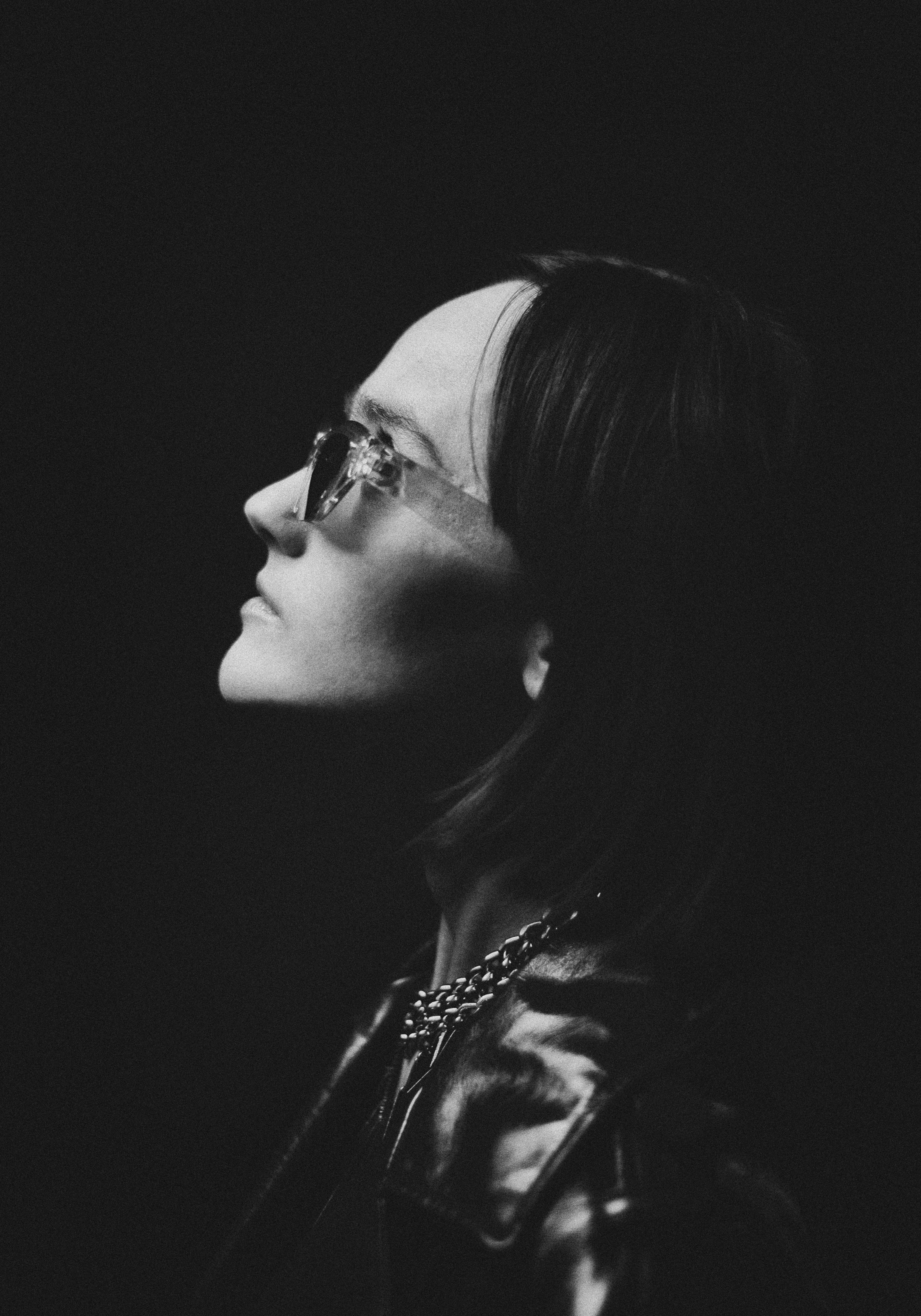 Donna in occhiali da sole e giacca di pelle che guarda in alto.