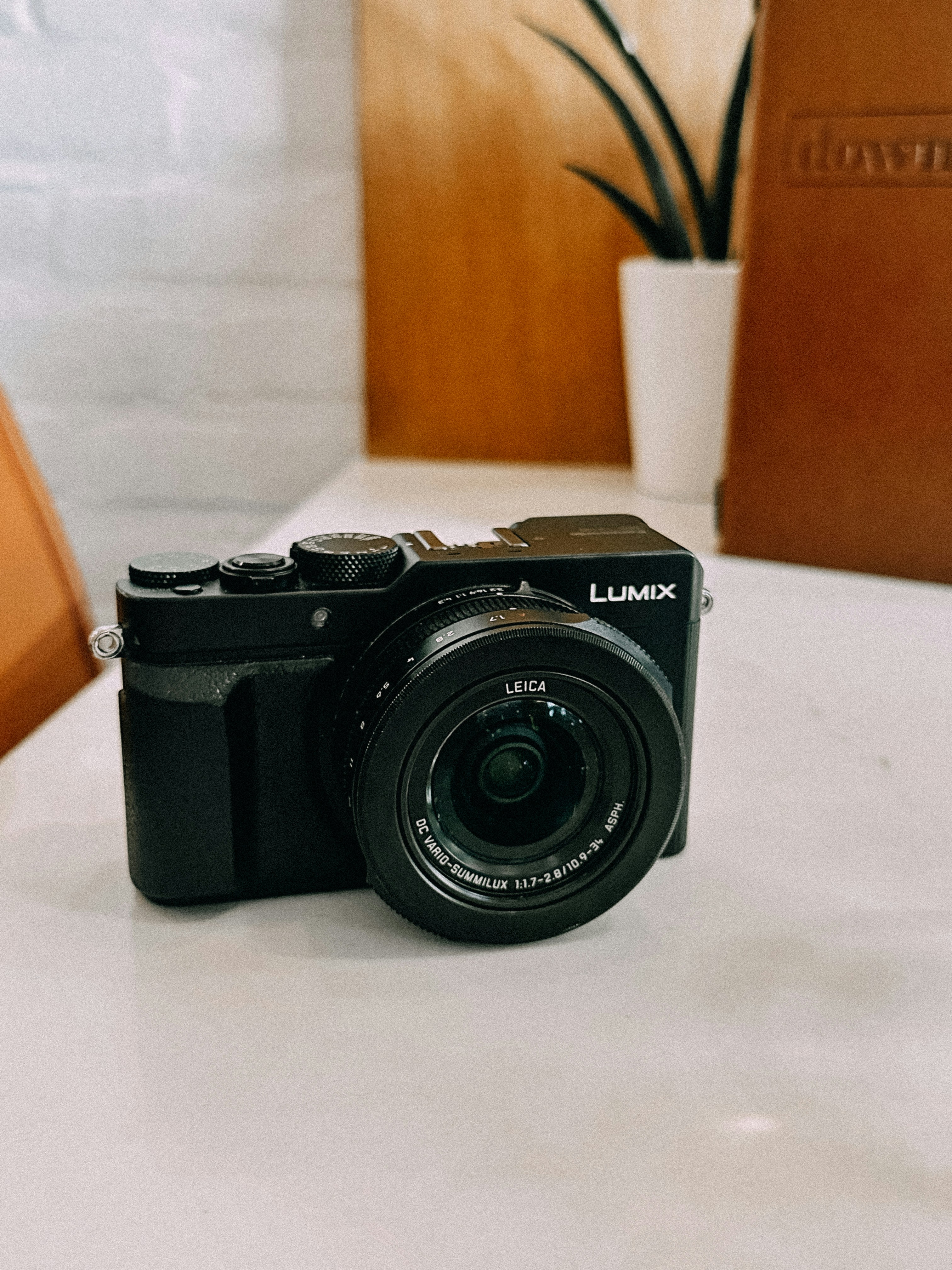 Una cámara digital lumix negra se encuentra sobre una mesa.