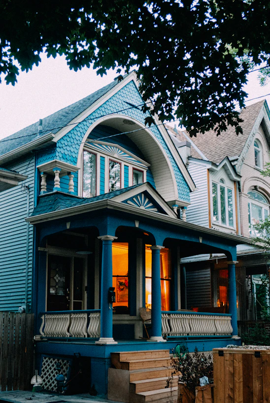 Blue house with warm lights on porch.