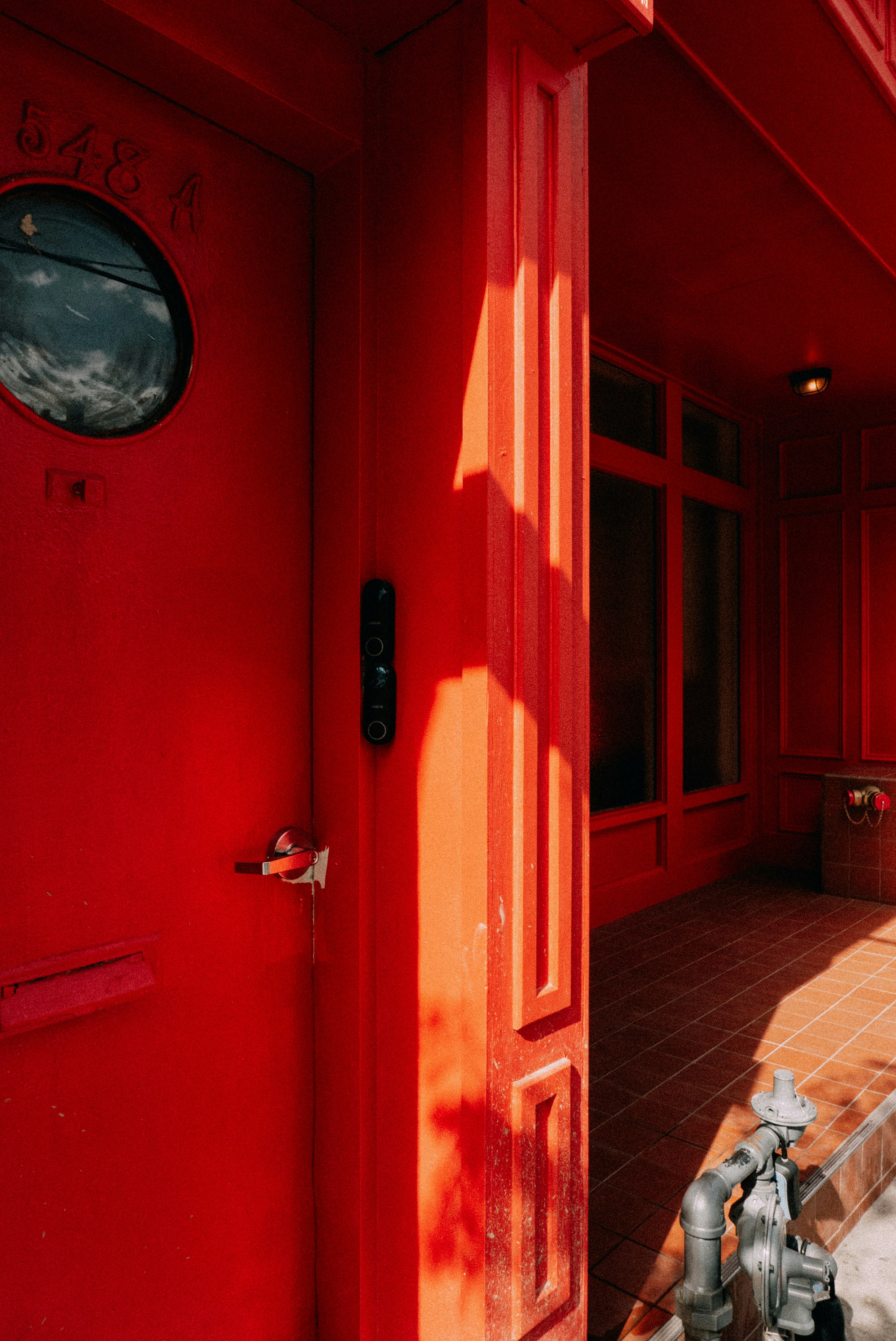 Una puerta de color rojo brillante con una ventana redonda.