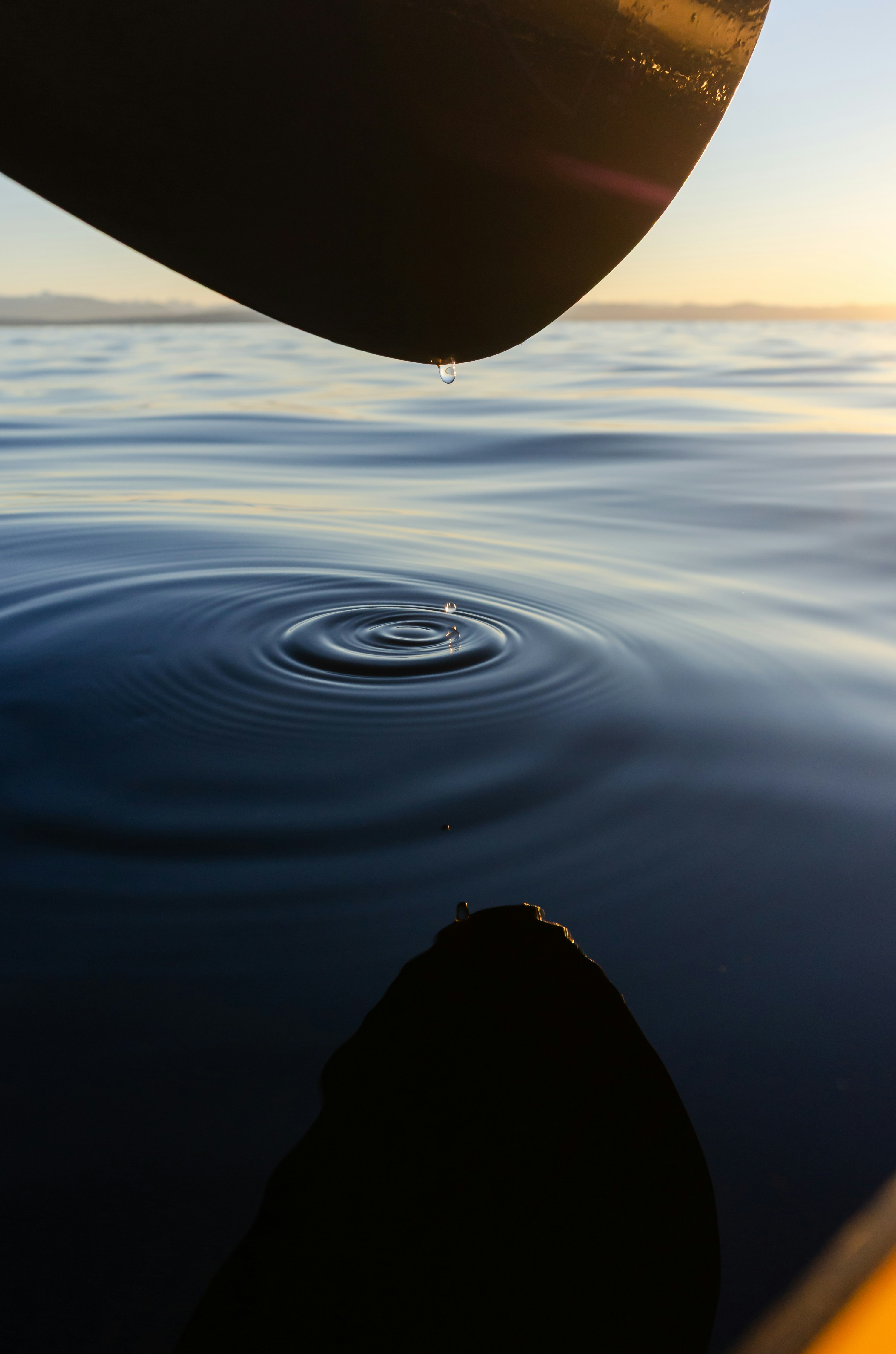 Water droplet falling into calm ocean ripples