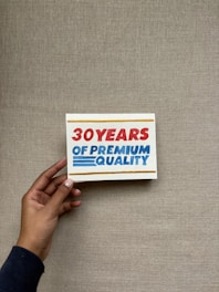 Hand holding sign with "30 years of premium quality"