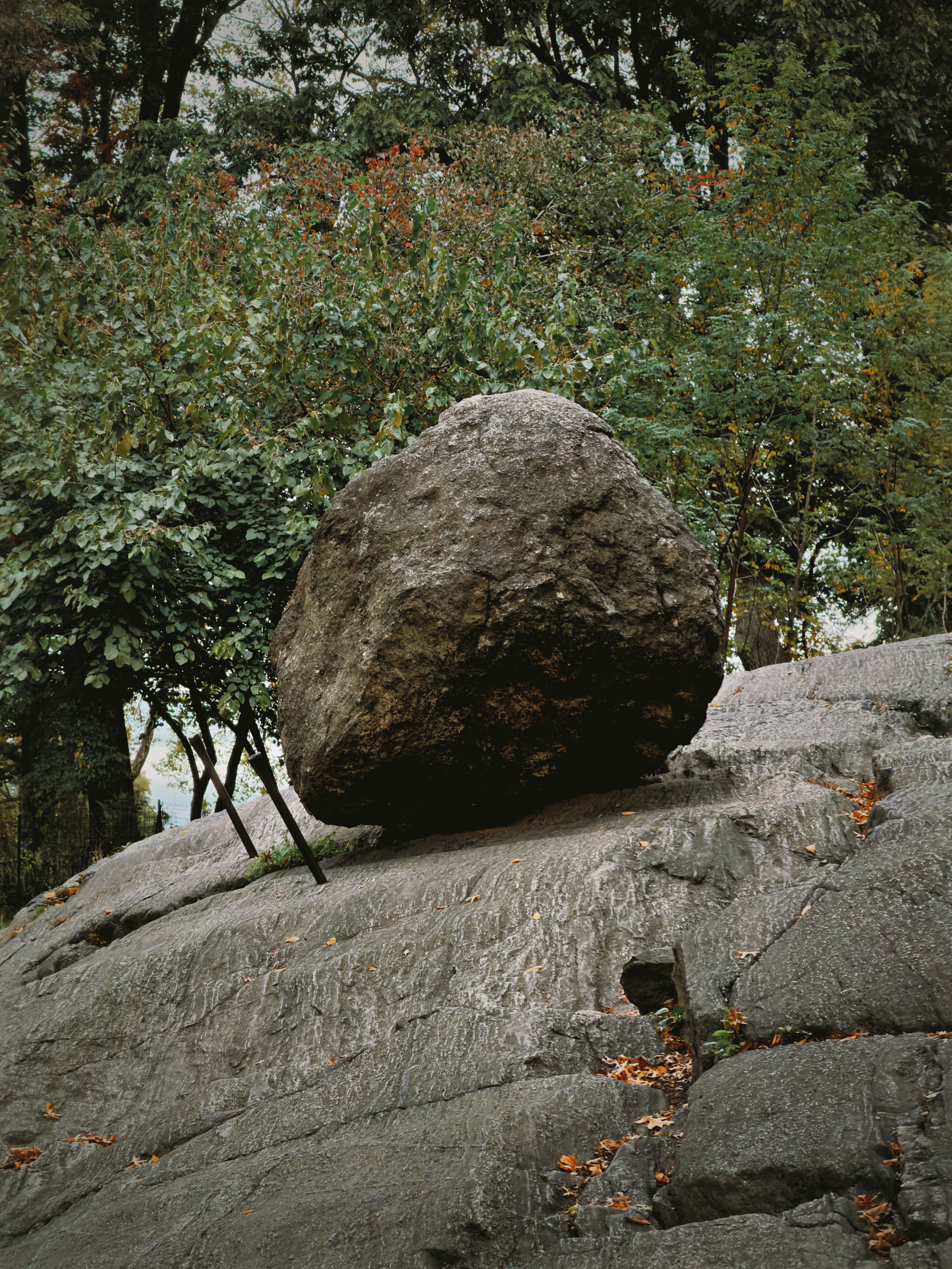A large boulder rests precariously on a rocky incline.