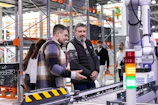 Men observe automated conveyor belt system in warehouse