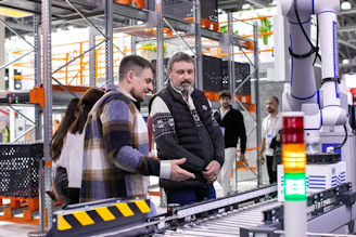 Men observe automated conveyor belt system in warehouse
