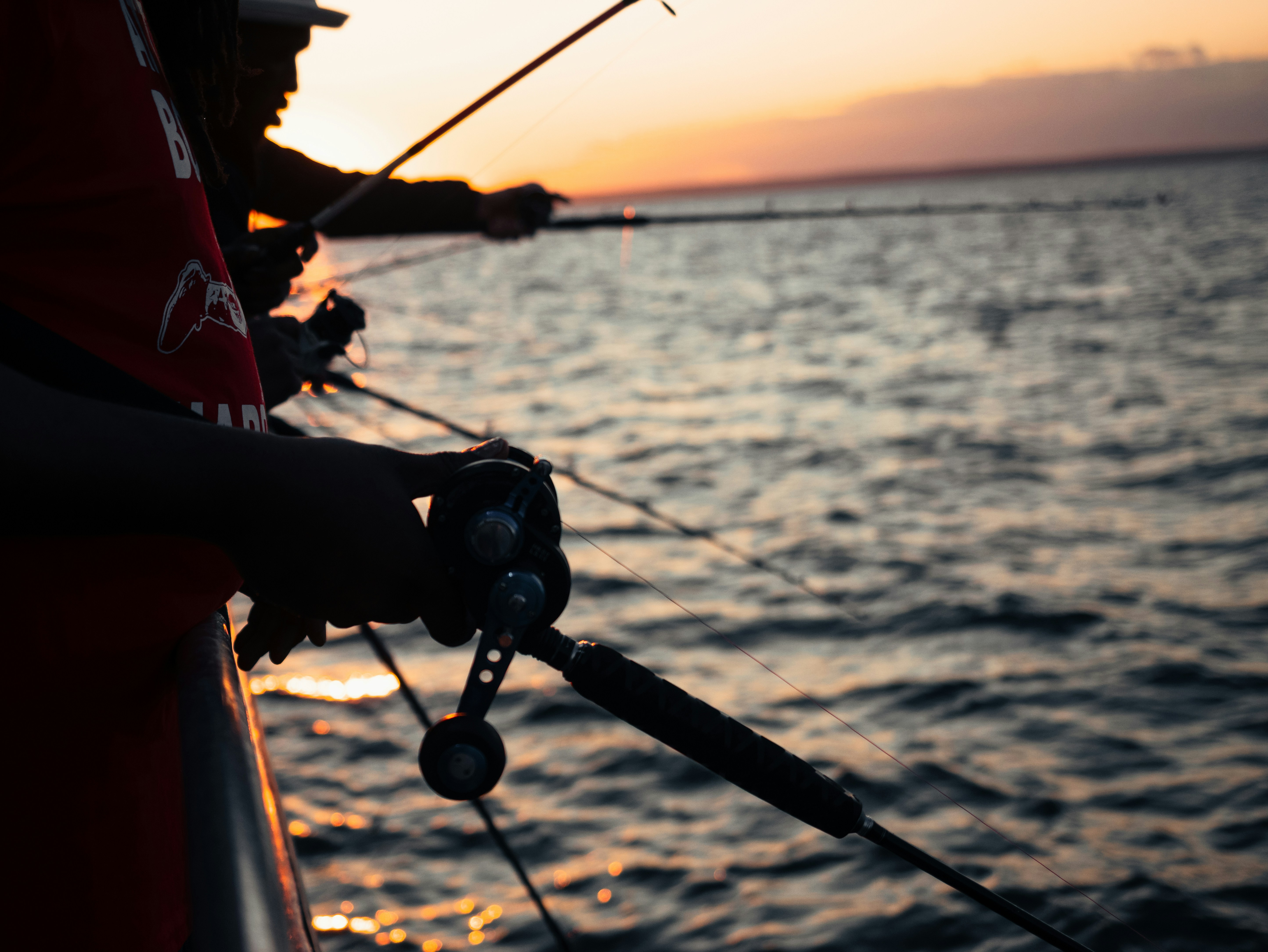 People fishing from a boat at sunset