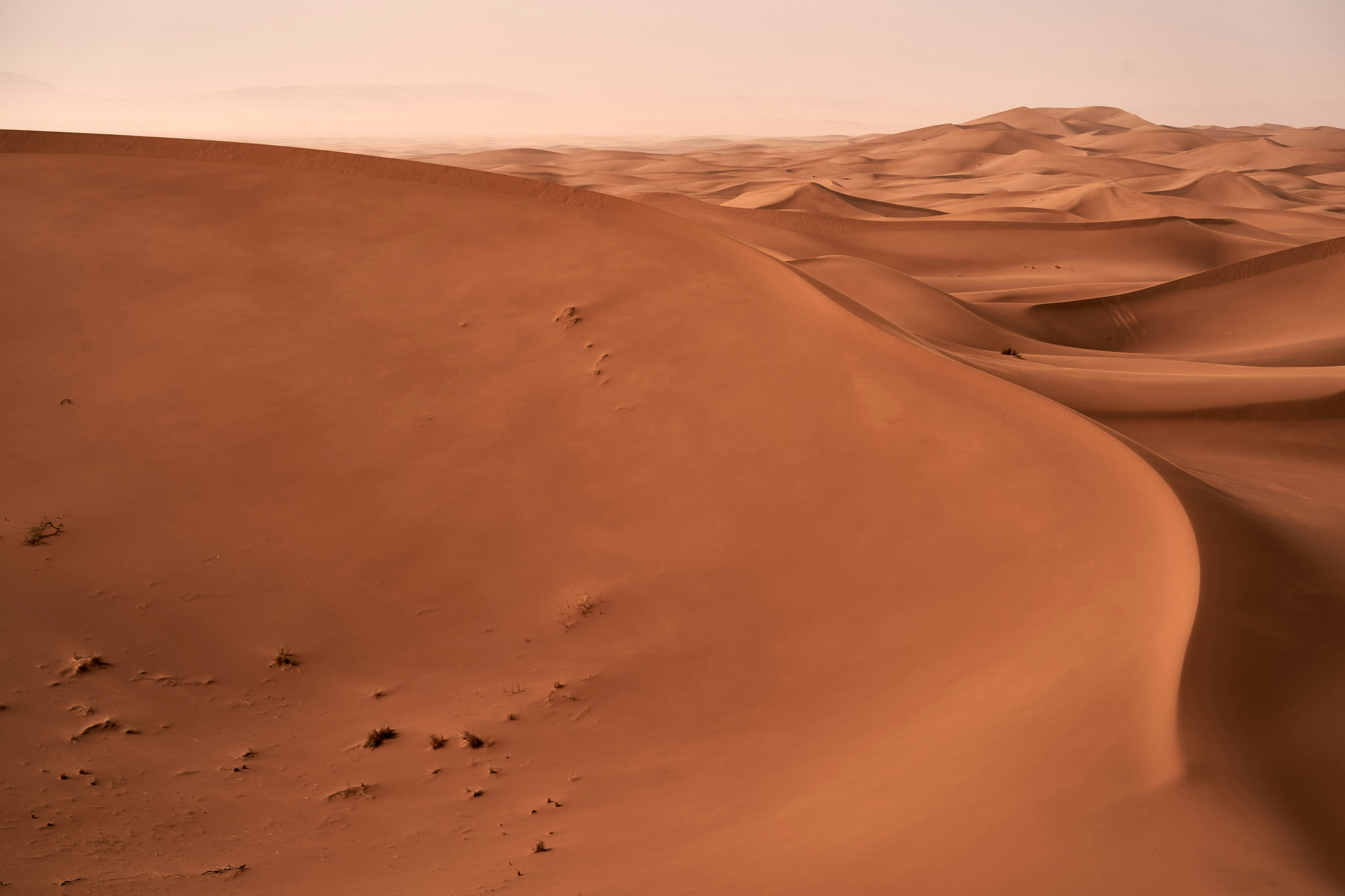 Vast desert sand dunes under a hazy sky