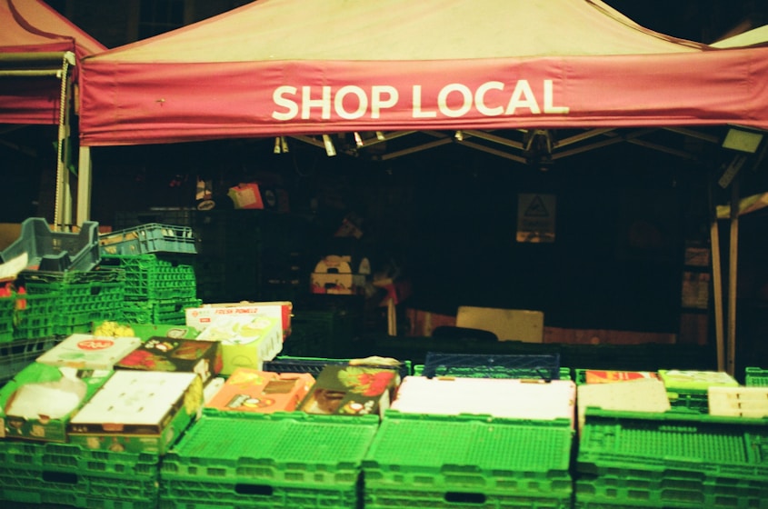 Market stall with 'shop local' banner and fresh produce