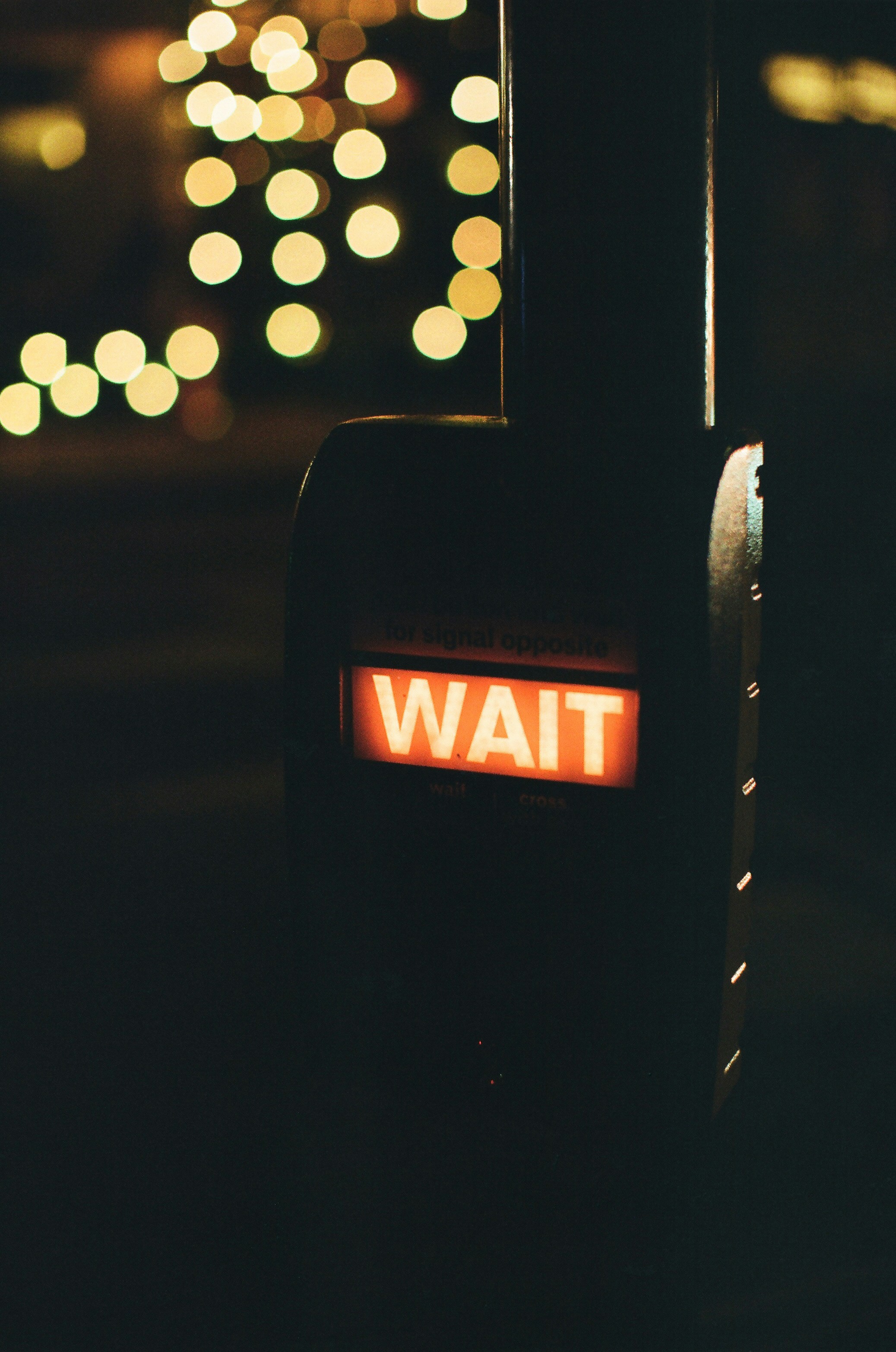 A glowing "wait" sign at night with bokeh lights
