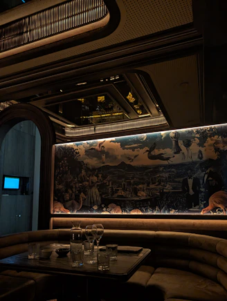 Luxurious booth seating with mural in dimly lit lounge.