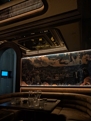 Luxurious booth seating with mural in dimly lit lounge.