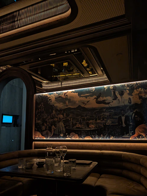 Luxurious booth seating with mural in dimly lit lounge.
