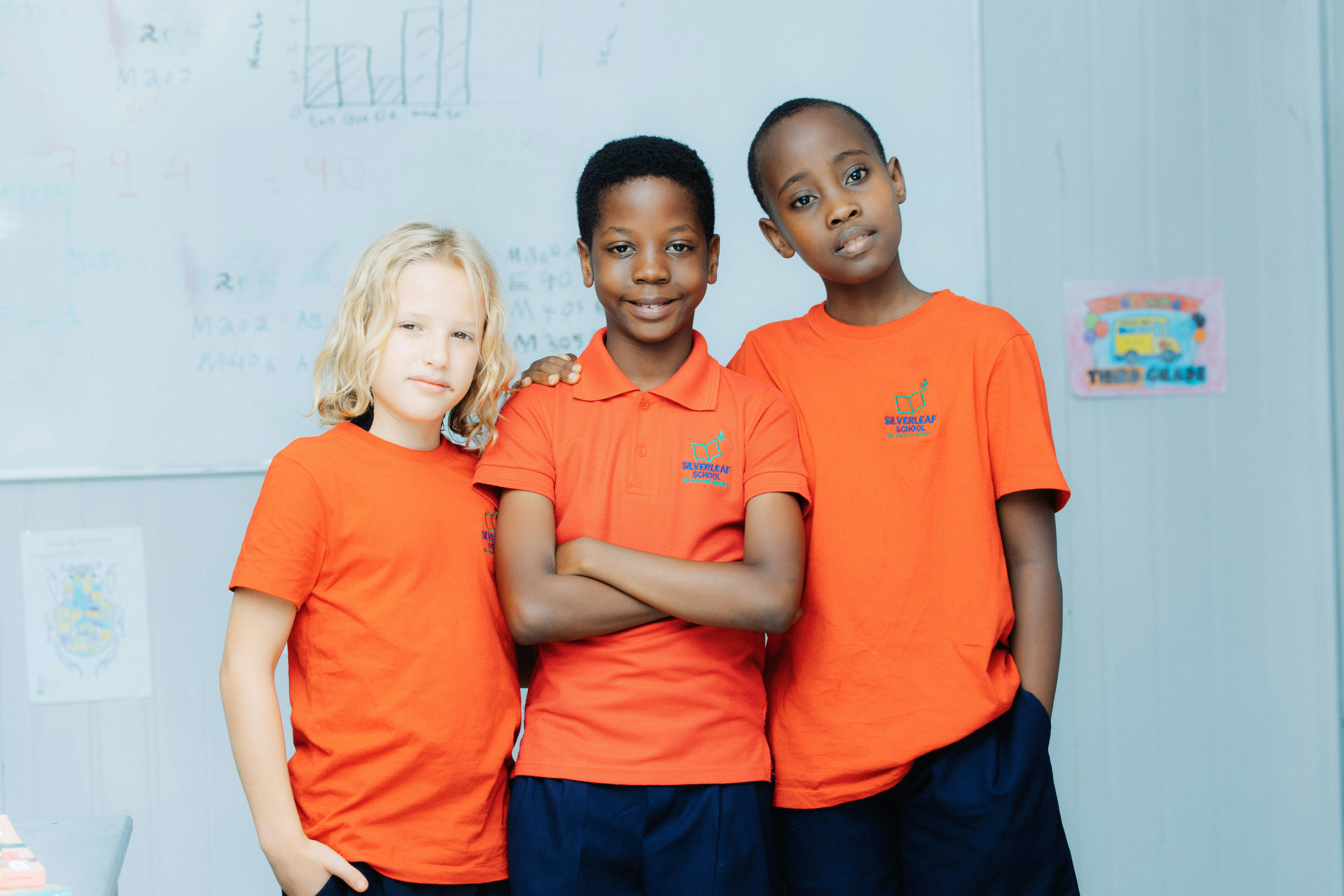 Three young boys in orange shirts standing together