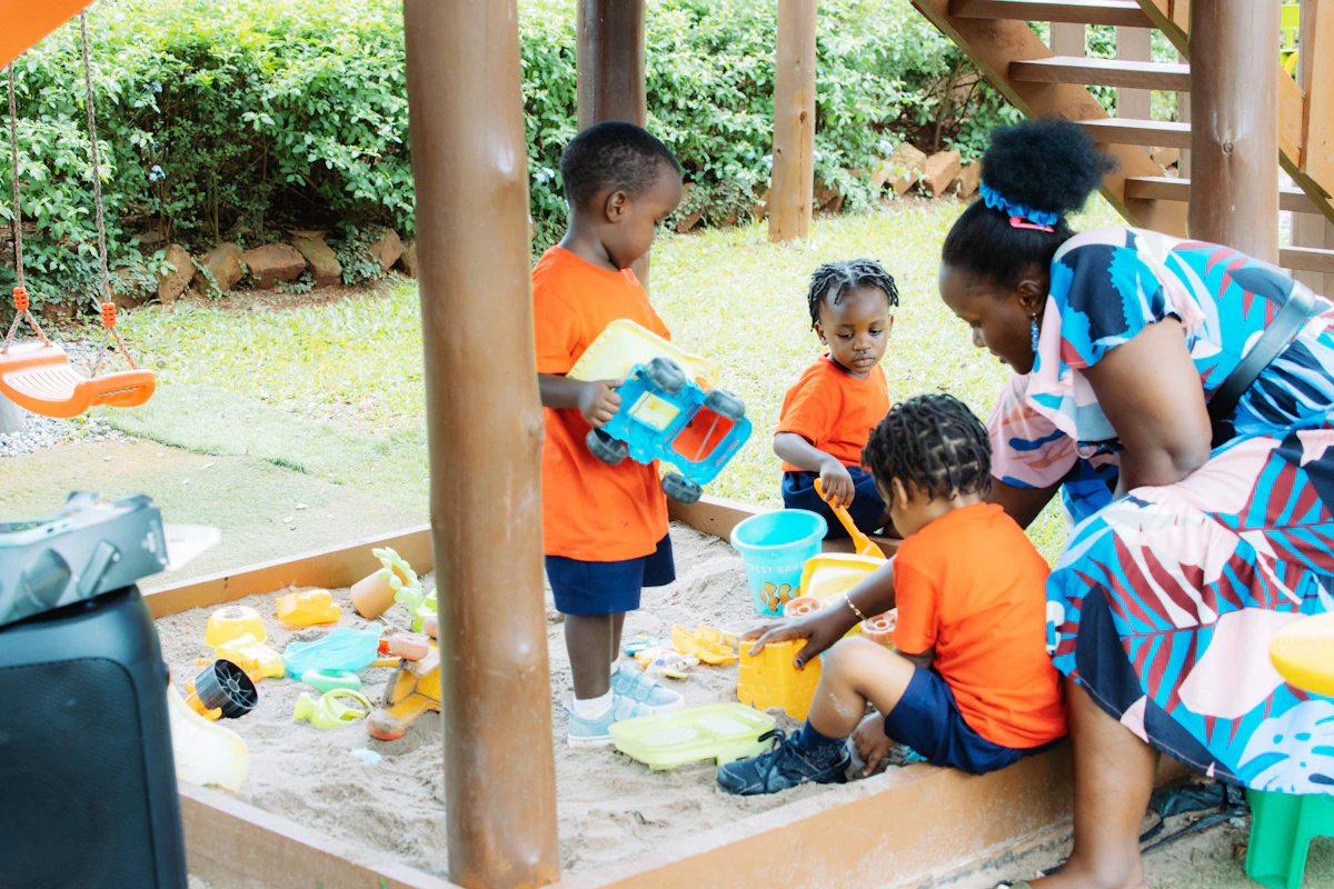 Kindergarten-Team beim Spielen mit Kindern im Sandkasten