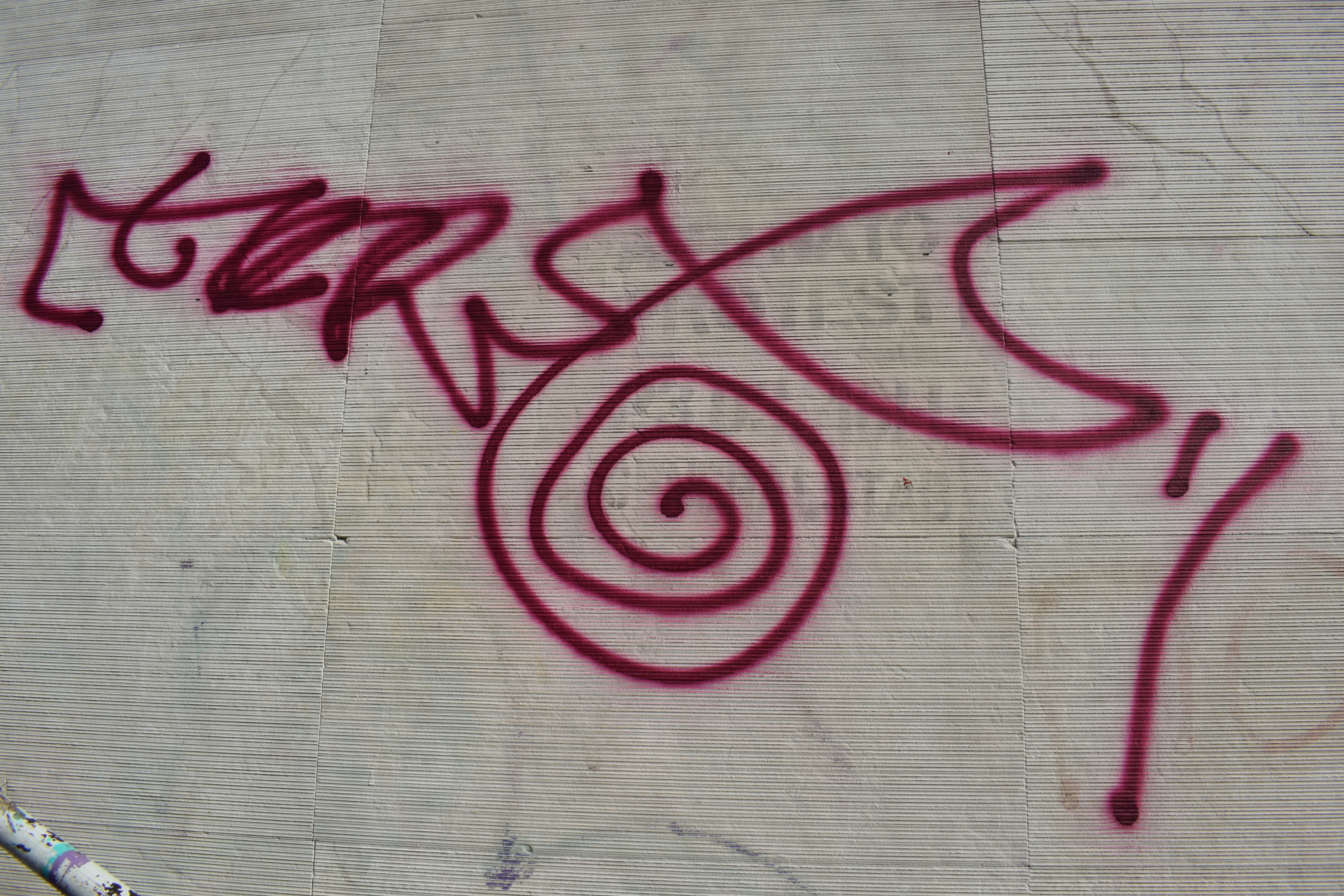Red graffiti tag with a spiral on a wall