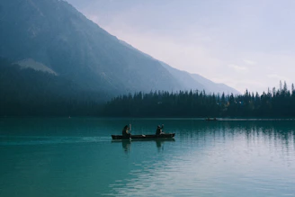 Two people in a canoe on a serene lake.