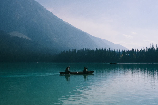 Two people in a canoe on a serene lake.