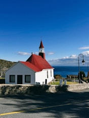 White church with red roof by the ocean.