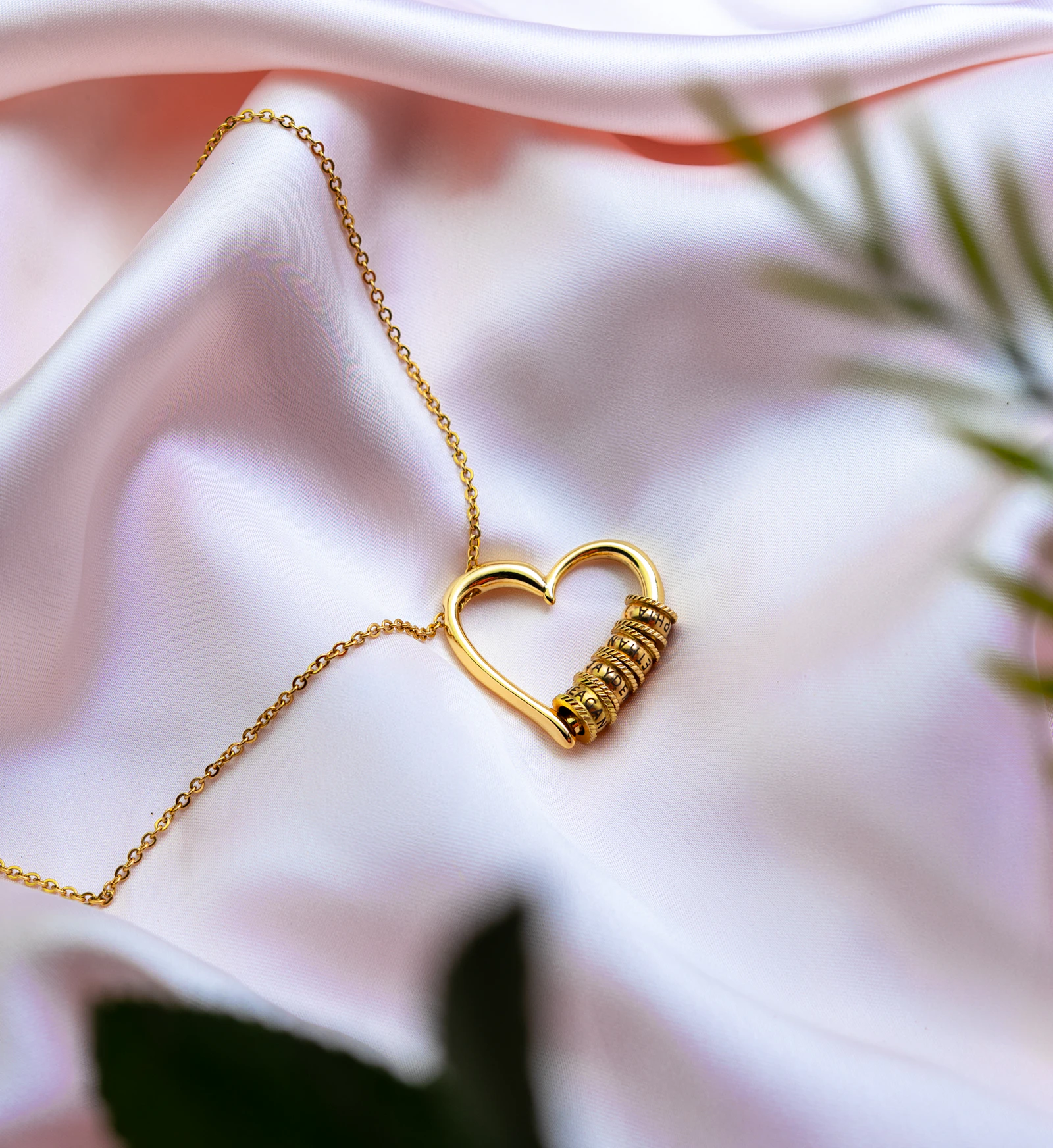 Gold heart necklace wrapped with ribbon on pink satin, prepared as a holiday birthday gift