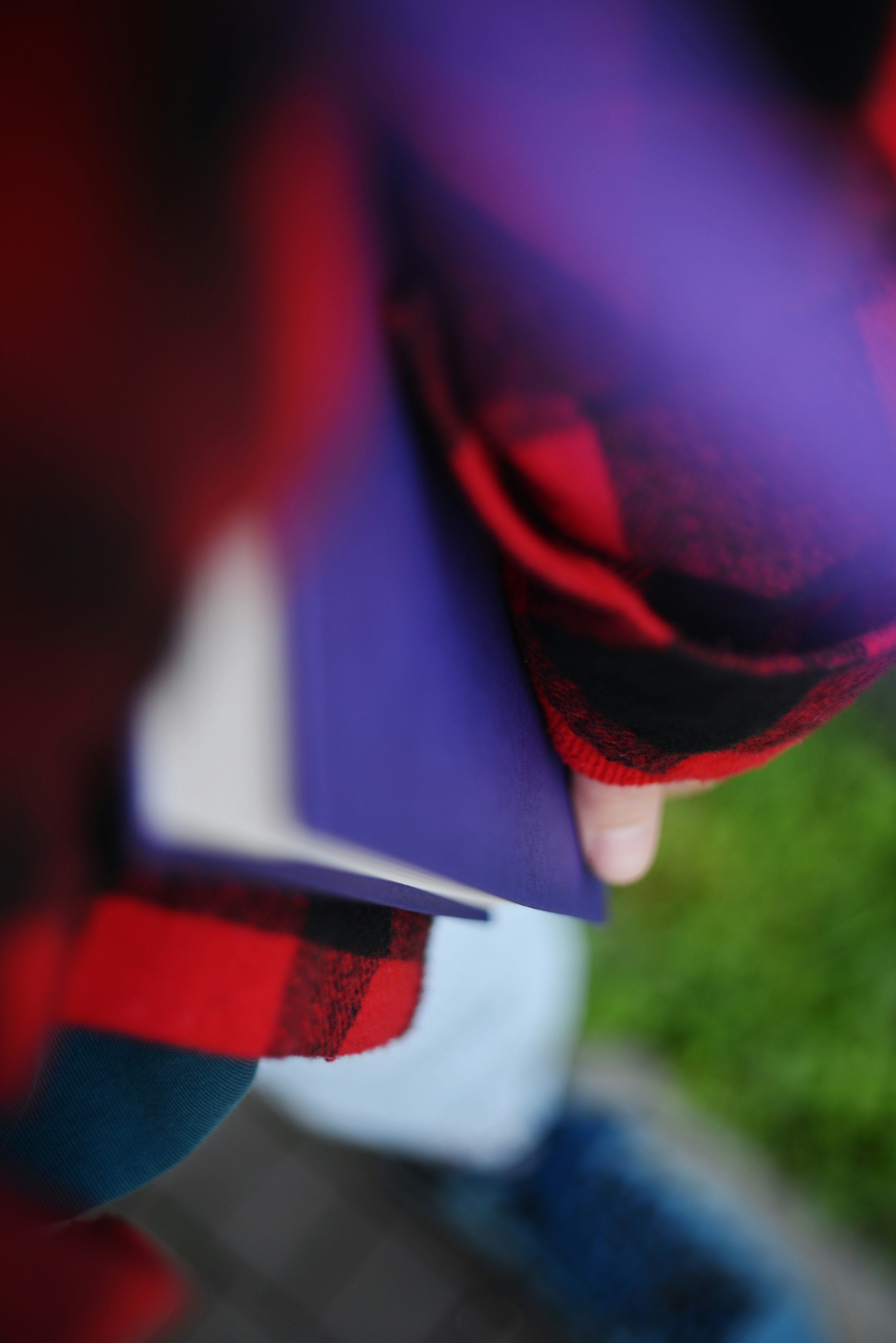 Person in red plaid jacket holding purple book