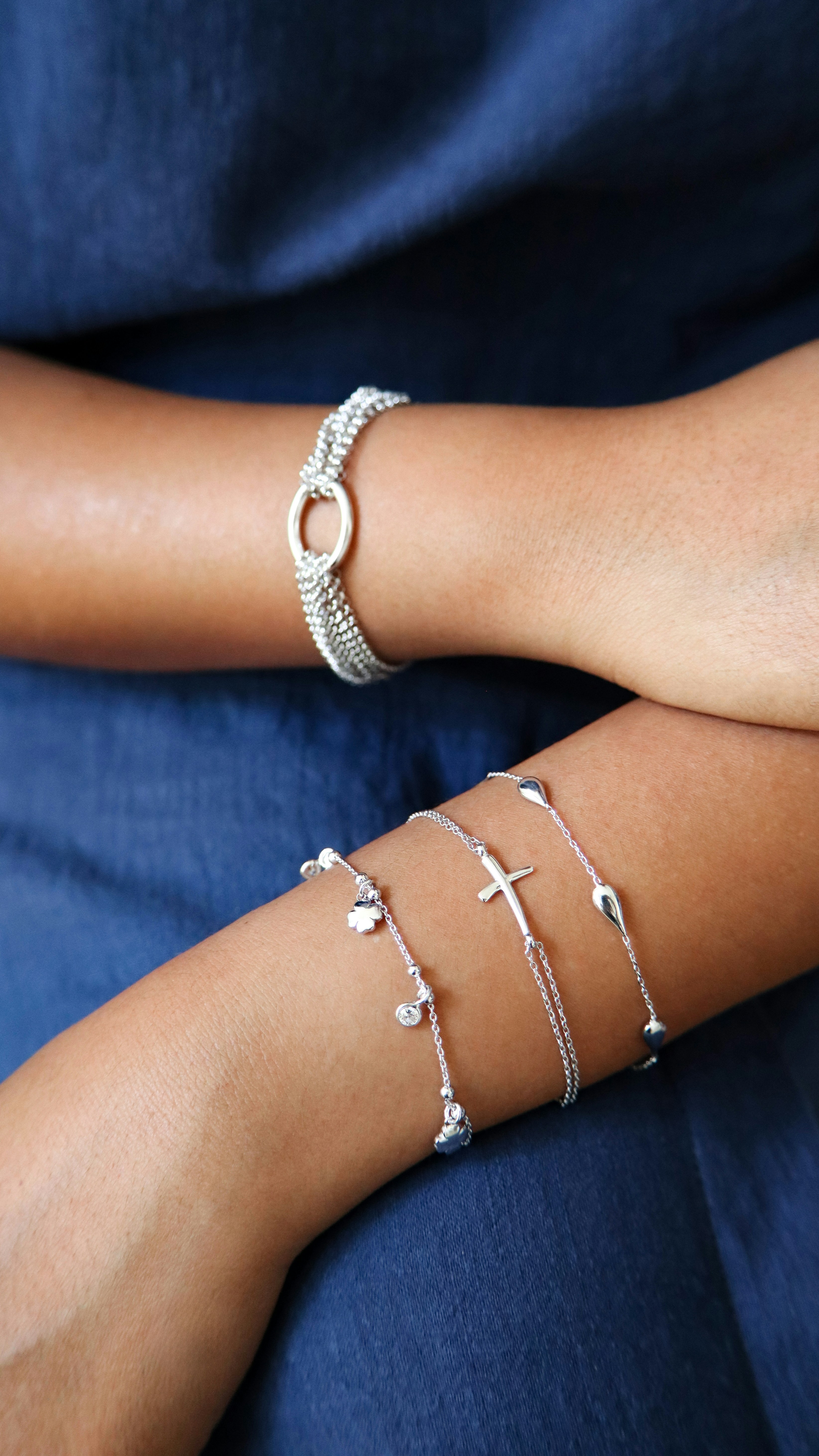 Two arms adorned with delicate silver bracelets.