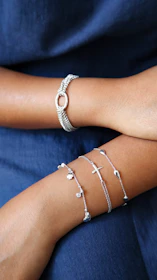 Two arms adorned with delicate silver bracelets.
