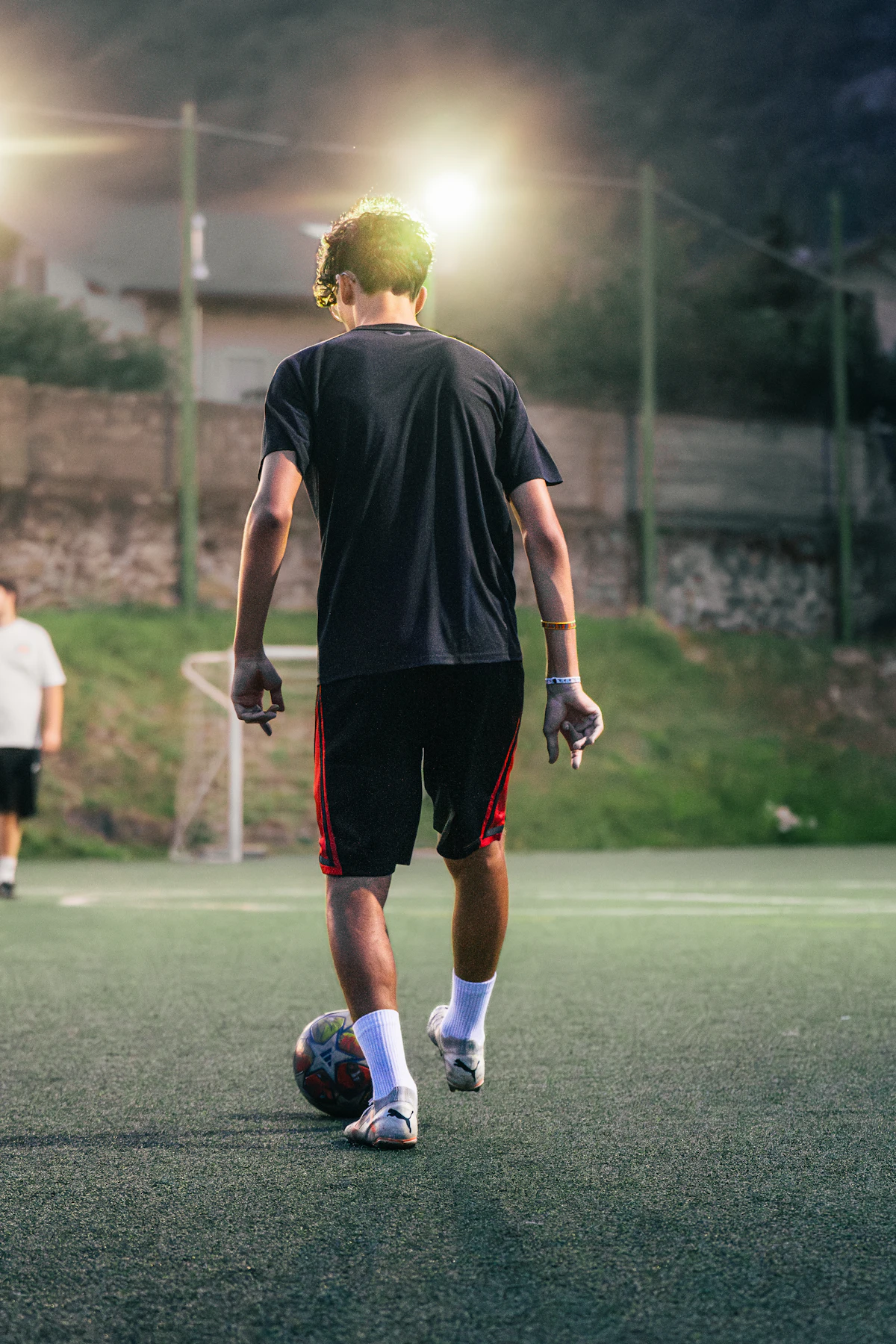 A player walks the ball out under a floodlight