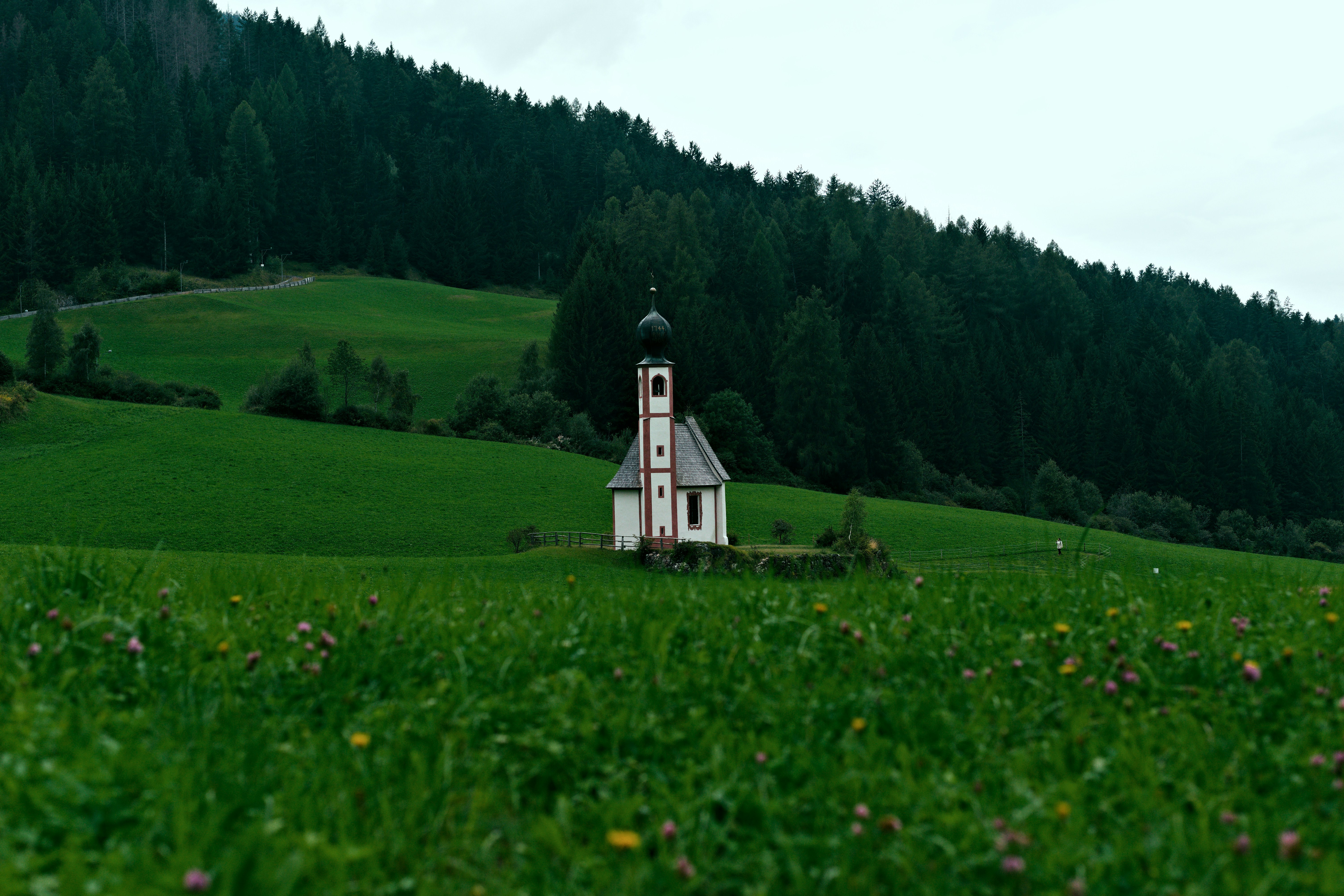 Small white church in a green grassy field.