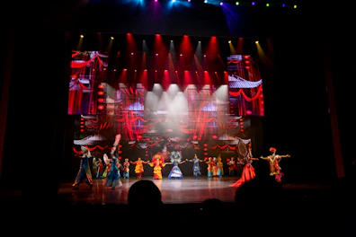 Performers on stage with colorful costumes and backdrop.