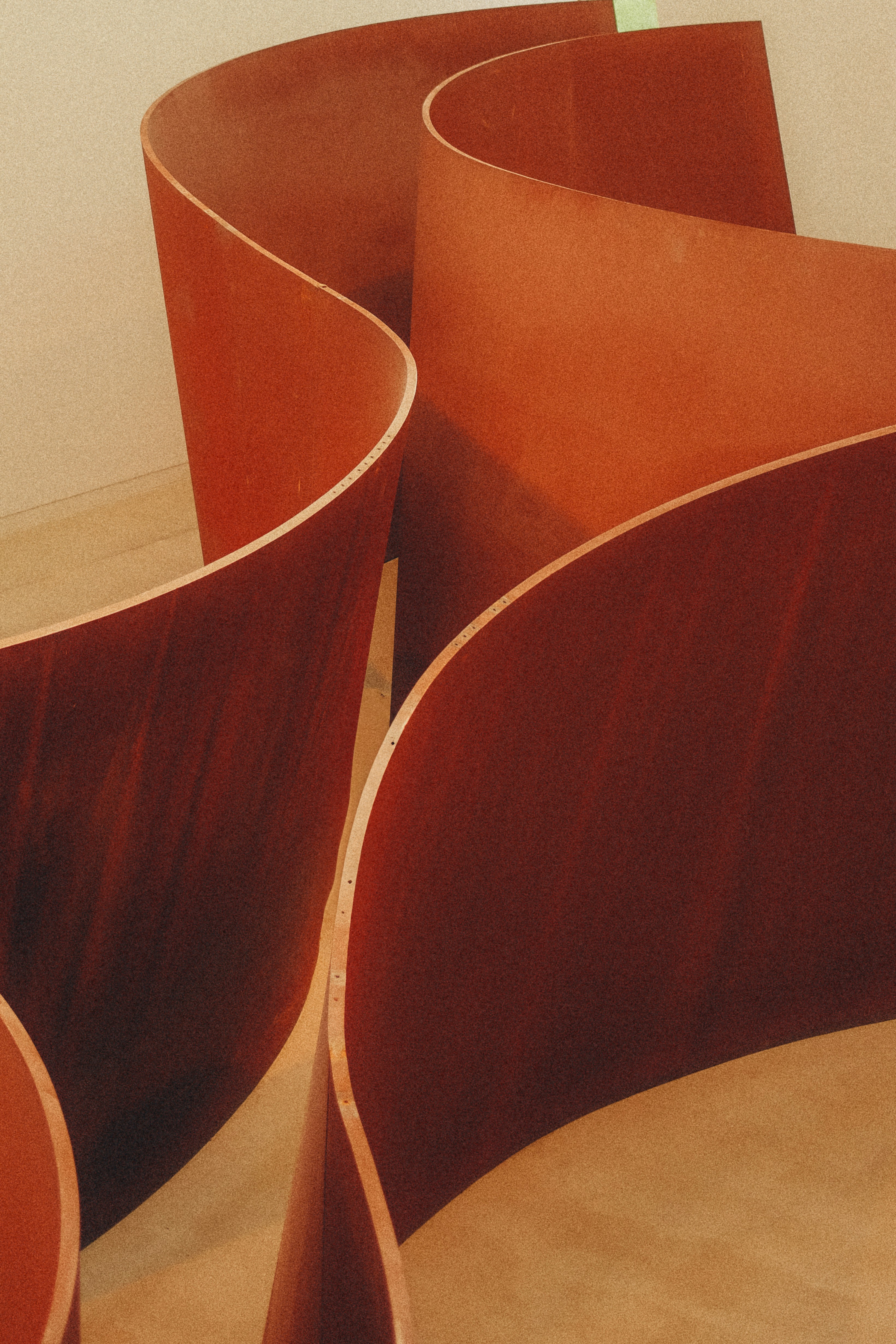 Curving red metal sculpture in a room